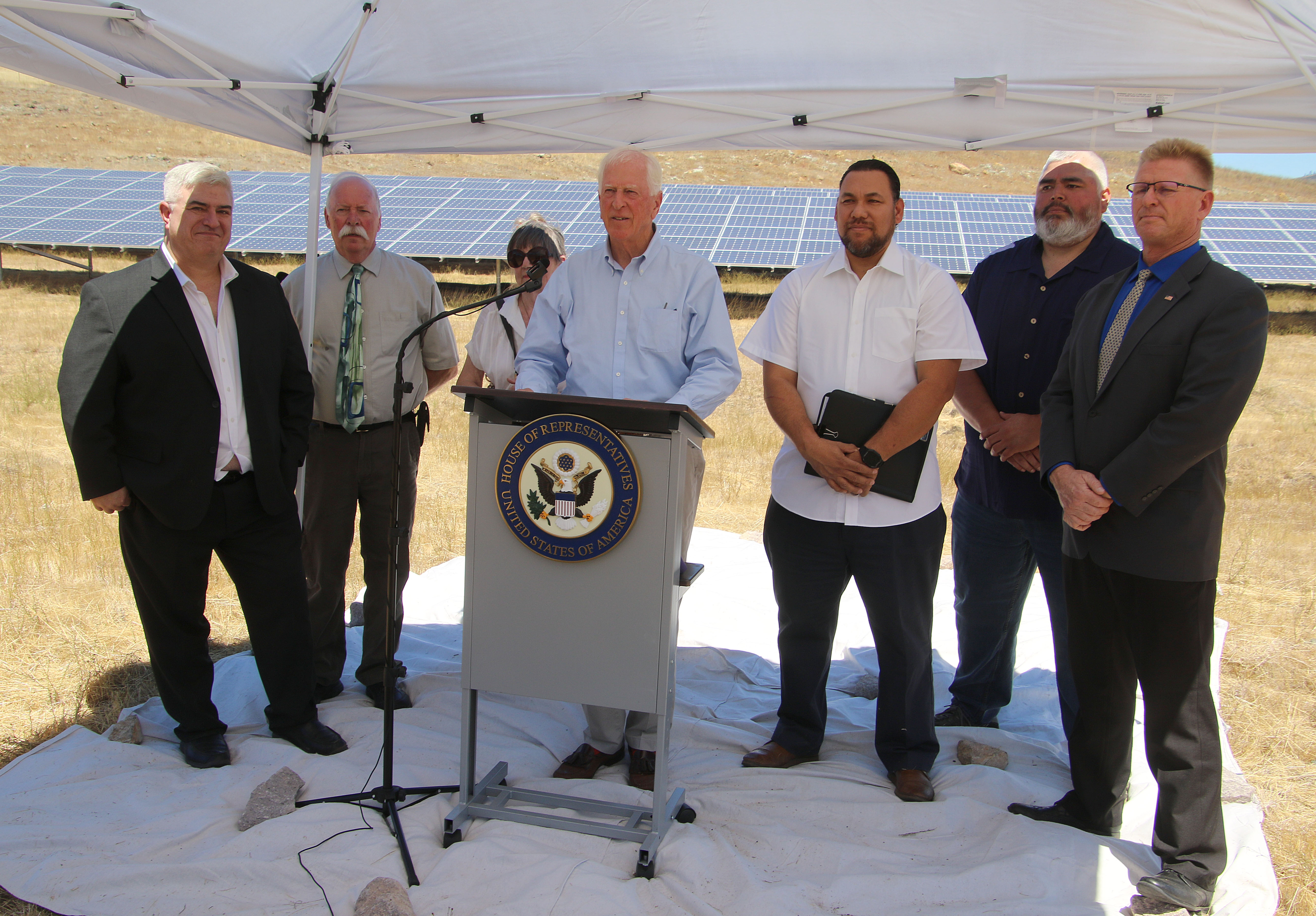 (From Left:) Michael Day, Gary Graves, Victoria Brando, Mike Thompson, Eddie Crandell, Moke Simon and Brock Falkenberg. Speakers stood in front of solar panels that were completed in 2012. The solar unit is made up of 1,176 240-watt panels covering 35,000 square feet. (Minenna Photography).