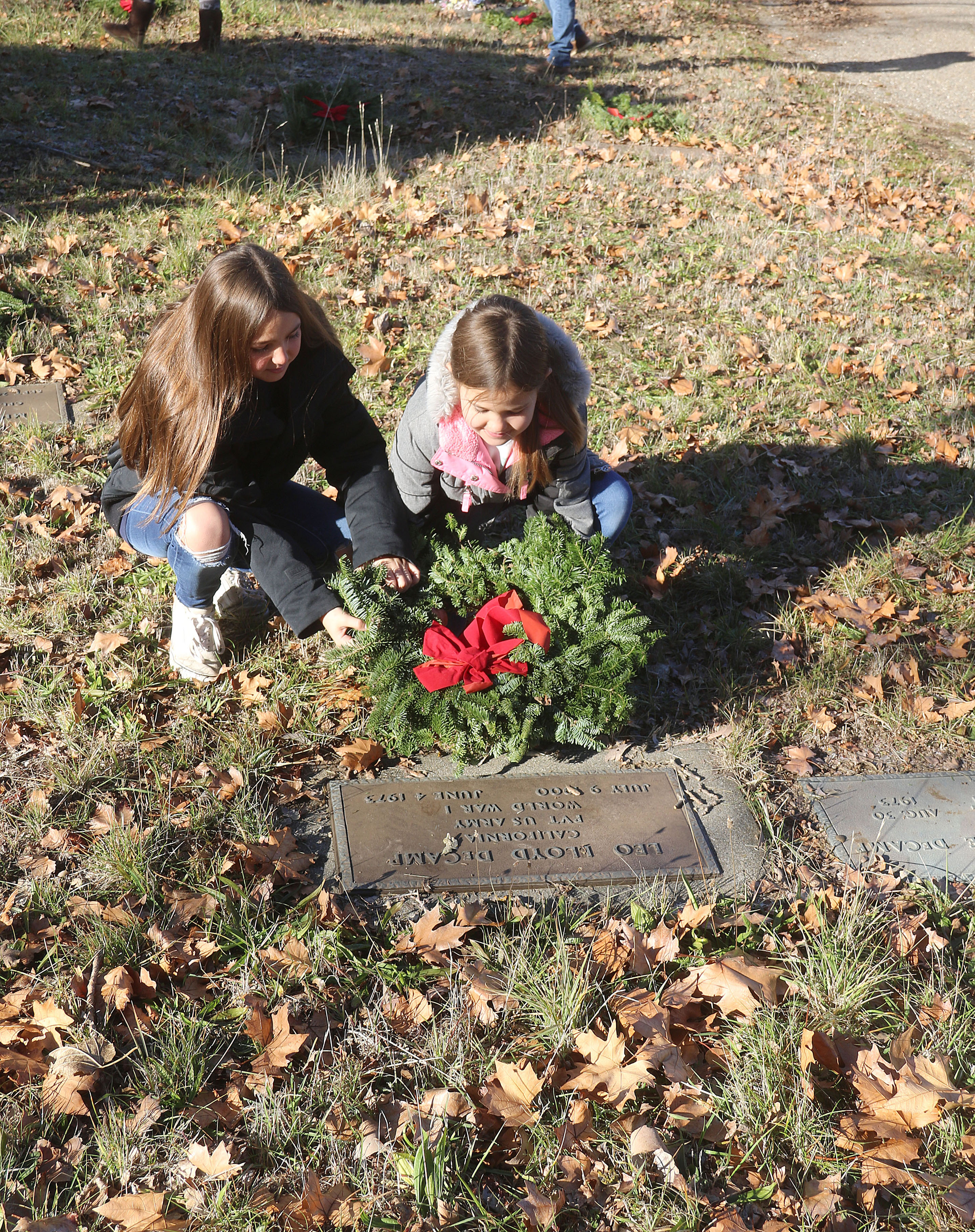 (From left:) Jaycie Innman, age 11 and Adrianna Innman, age 8 place a wreath in honor of Leo Decamp, a Wold War l private in the Unites States Army who is just one on the many veterans buried at the cemetery in Lower Lake. (Minenna Photography)