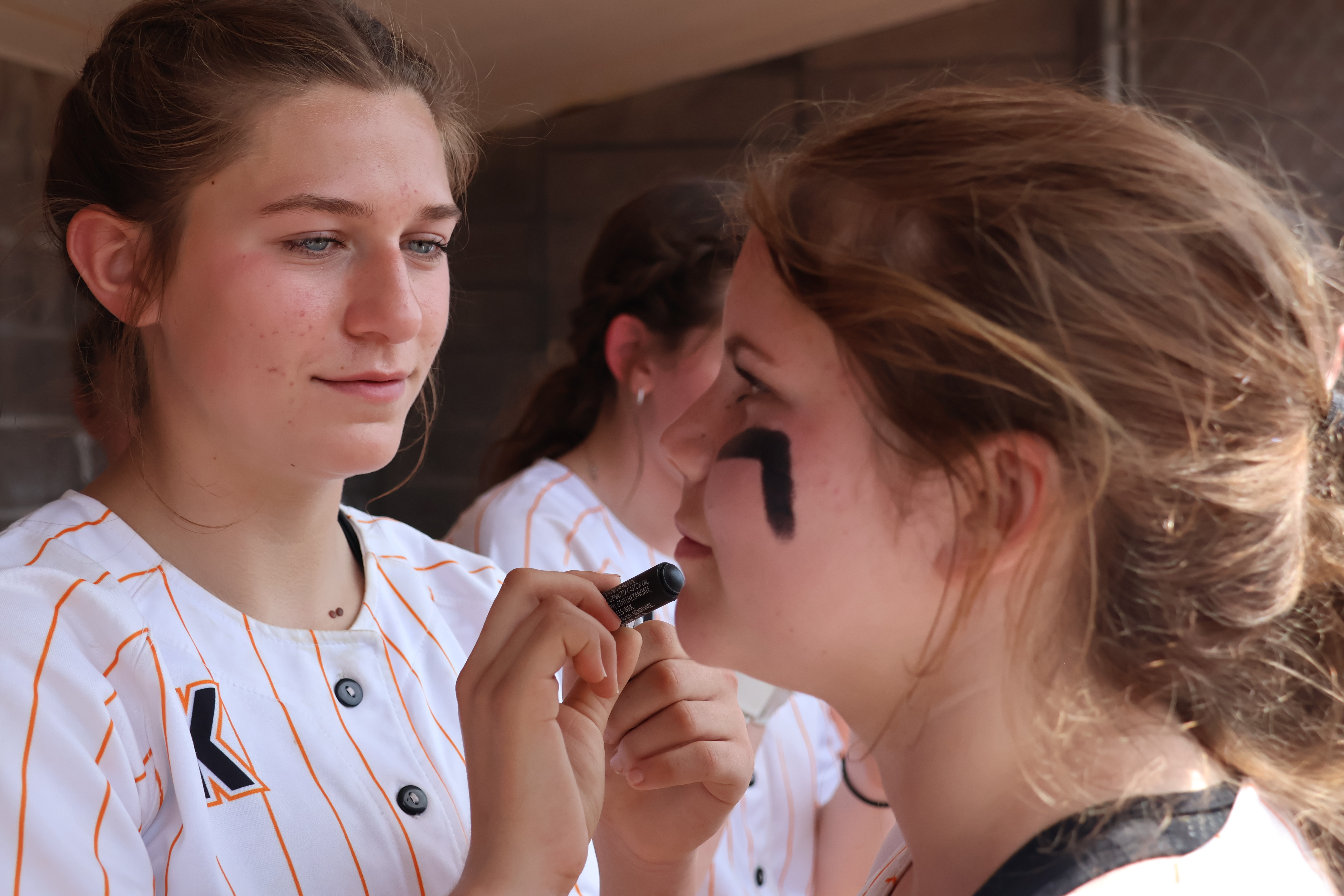 Mati Mateer applies some eye black to teammate Olivia Rabe in the dugout prior to the start of Saturday's non-league game against Hoopa at Mendocino College in Ukiah. (Photos by Brian Sumpter)