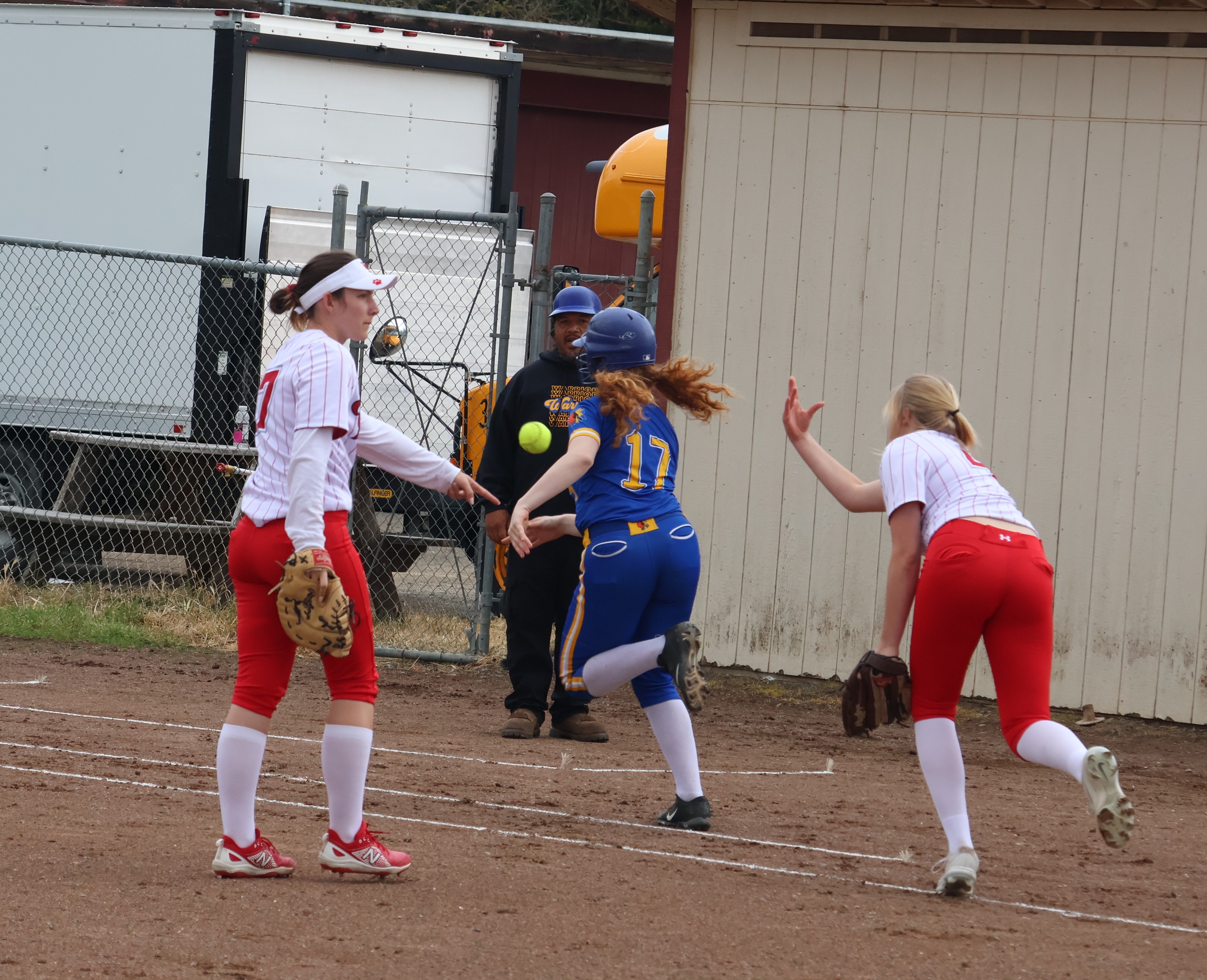 Upper Lake pitcher Aimee Schaefers underhands the ball to teammate Nya Marcks covering at first base on a slow chopper. First baseman Paris Kleier (far left) points out that the ball was foul, which was the ruling on the field. (Photos by Brian Sumpter)