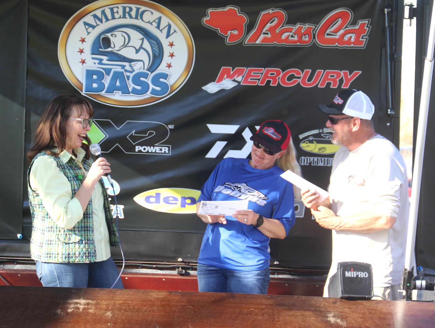 (From left:) Laura McAndrews Sammel, CEO of the Lake County Chamber of Commerce presents Monica and John Hampel their checks for $1,000 for their big fish. (Minenna Photography)