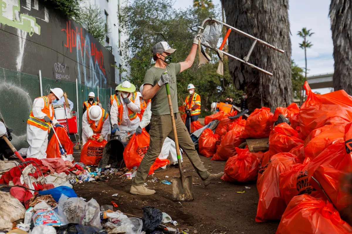 Gov. Gavin Newsom helps cleanup a homeless encampment along a freeway in San Diego, on Jan. 12, 2022. File Photo by Mike Blake, Reuters