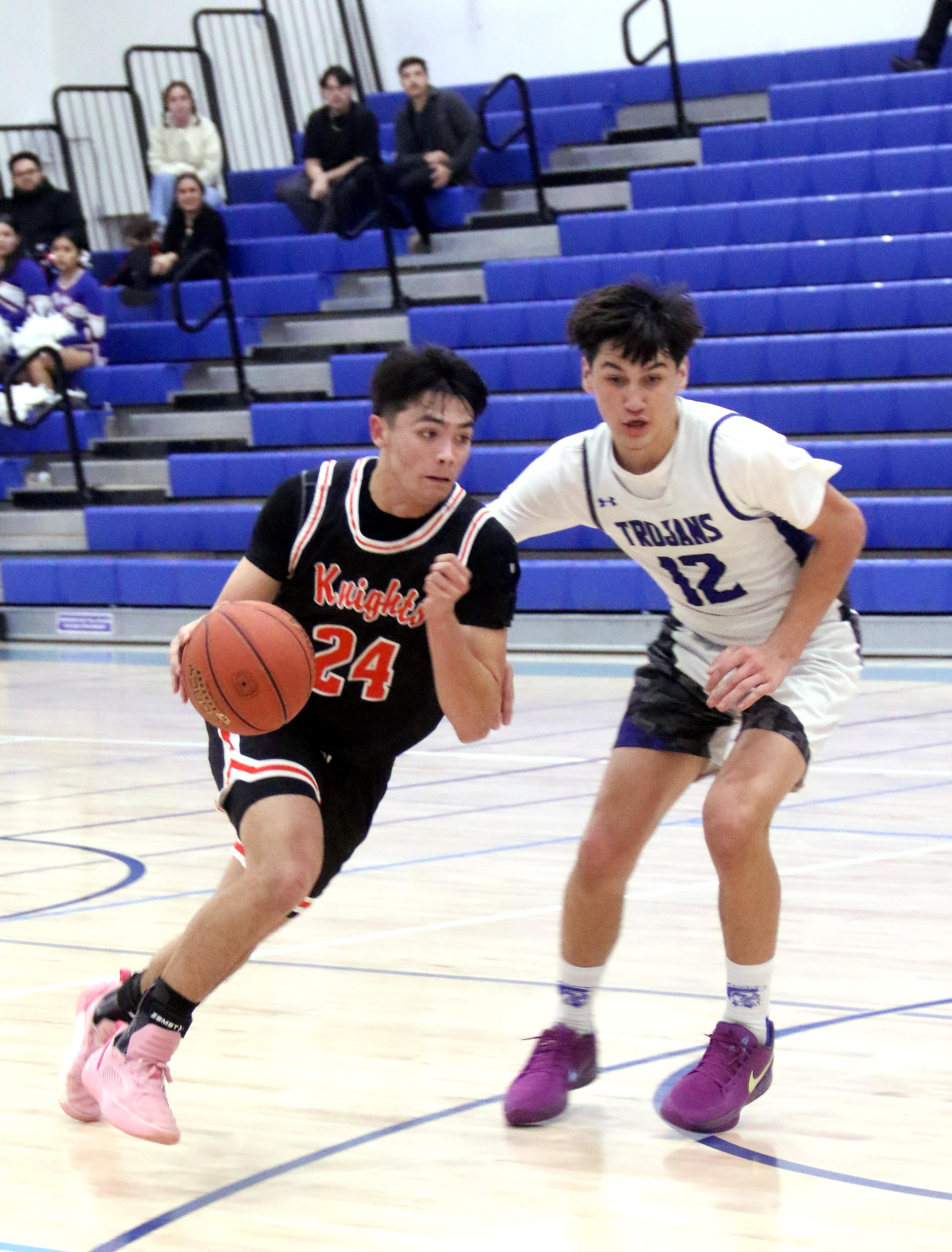 Kelseyville's Kyle Watkins (24) is guarded by Lower Lake's Noah Hakala as Watkins bring the ball down the court. The Knights took the win against the host Trojans. (Minenna Photography.)
