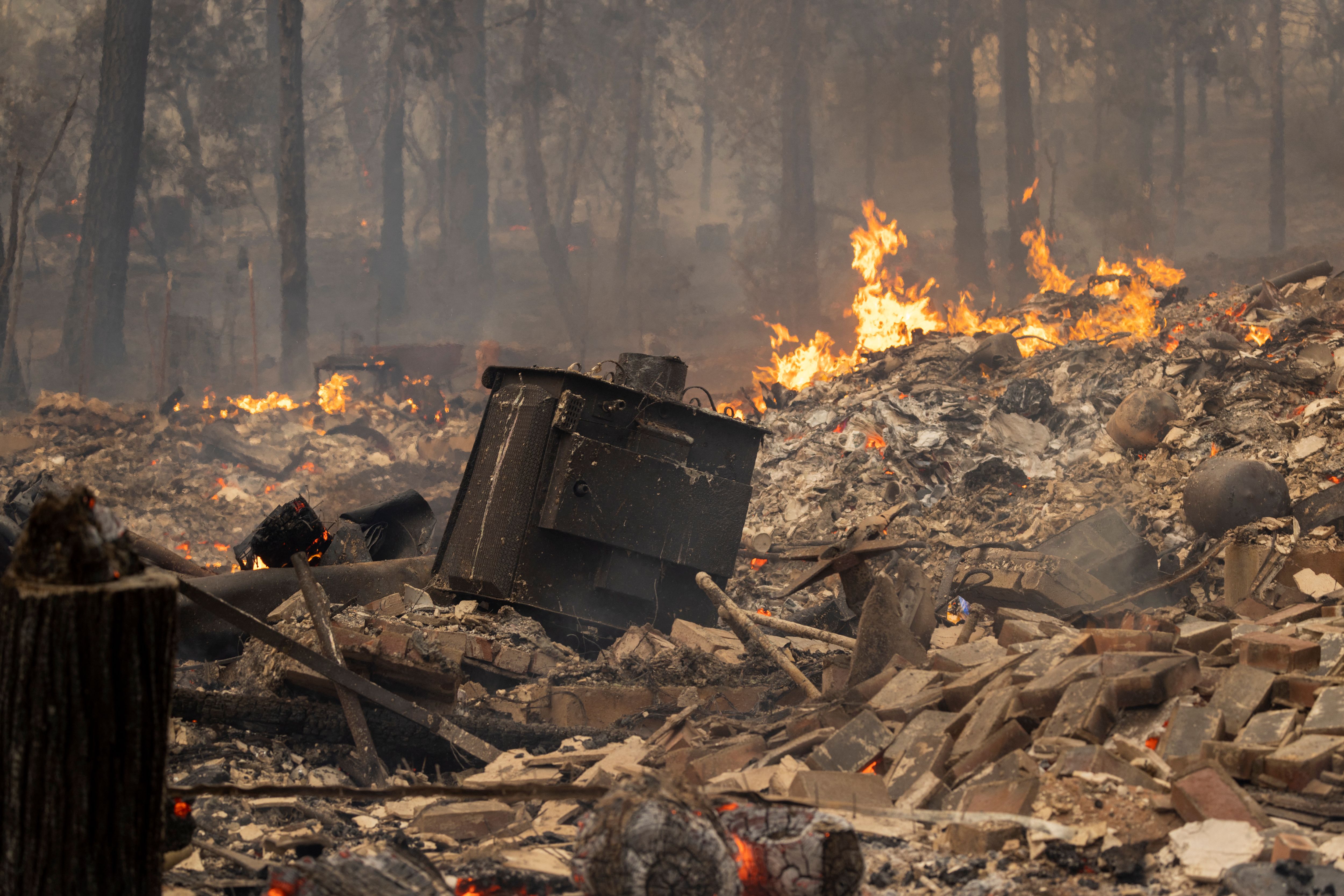 The ruins of a home destroyed in the Oak Fire smolder near Midpines, northeast of Mariposa, Calif., on Saturday, July 23, 2022. 