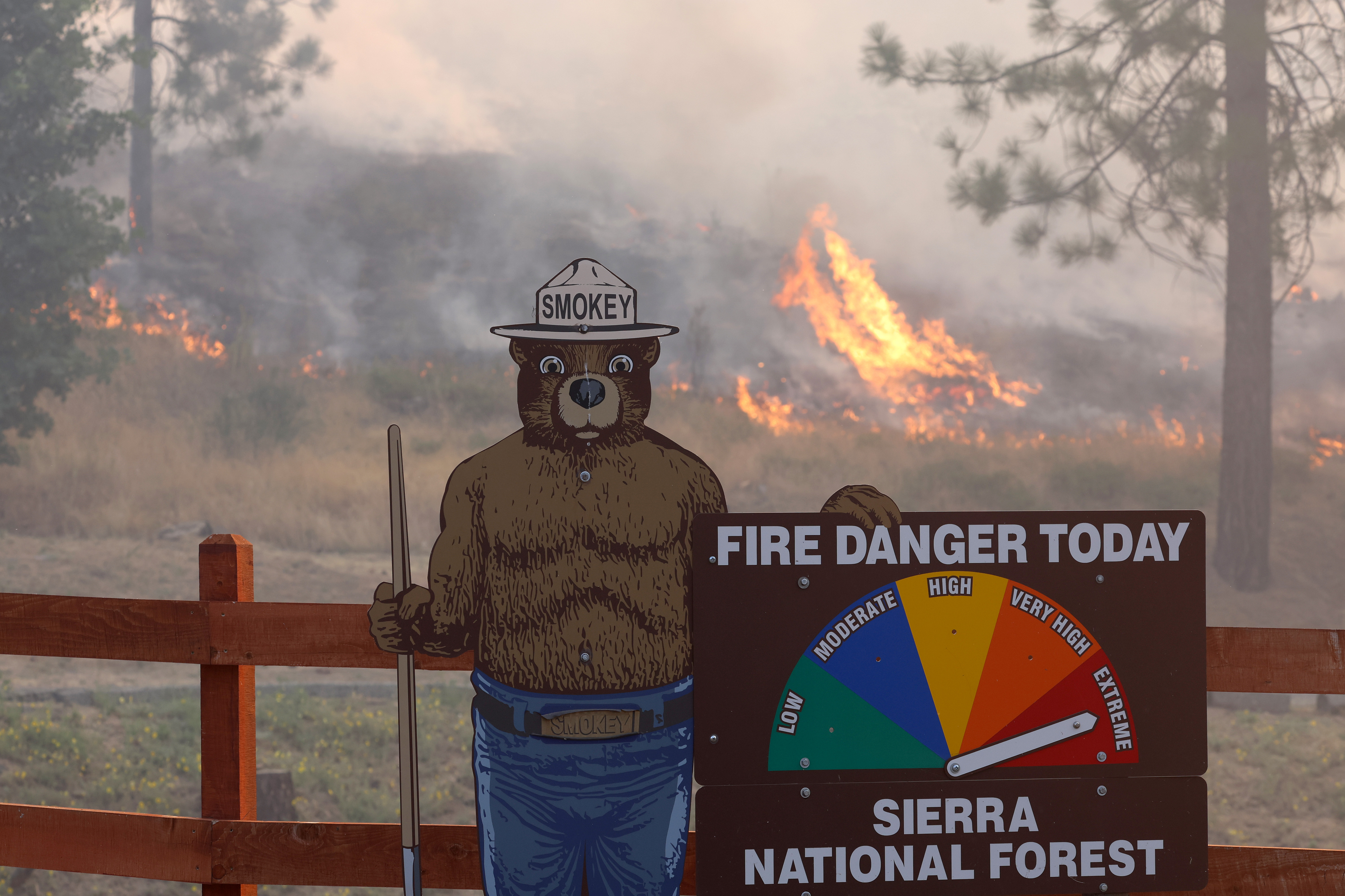 Fire burns near a Smokey Bear fire warning sign as the Oak Fire burns through the area on Sunday, July 24, 2022 near Jerseydale, Calif.