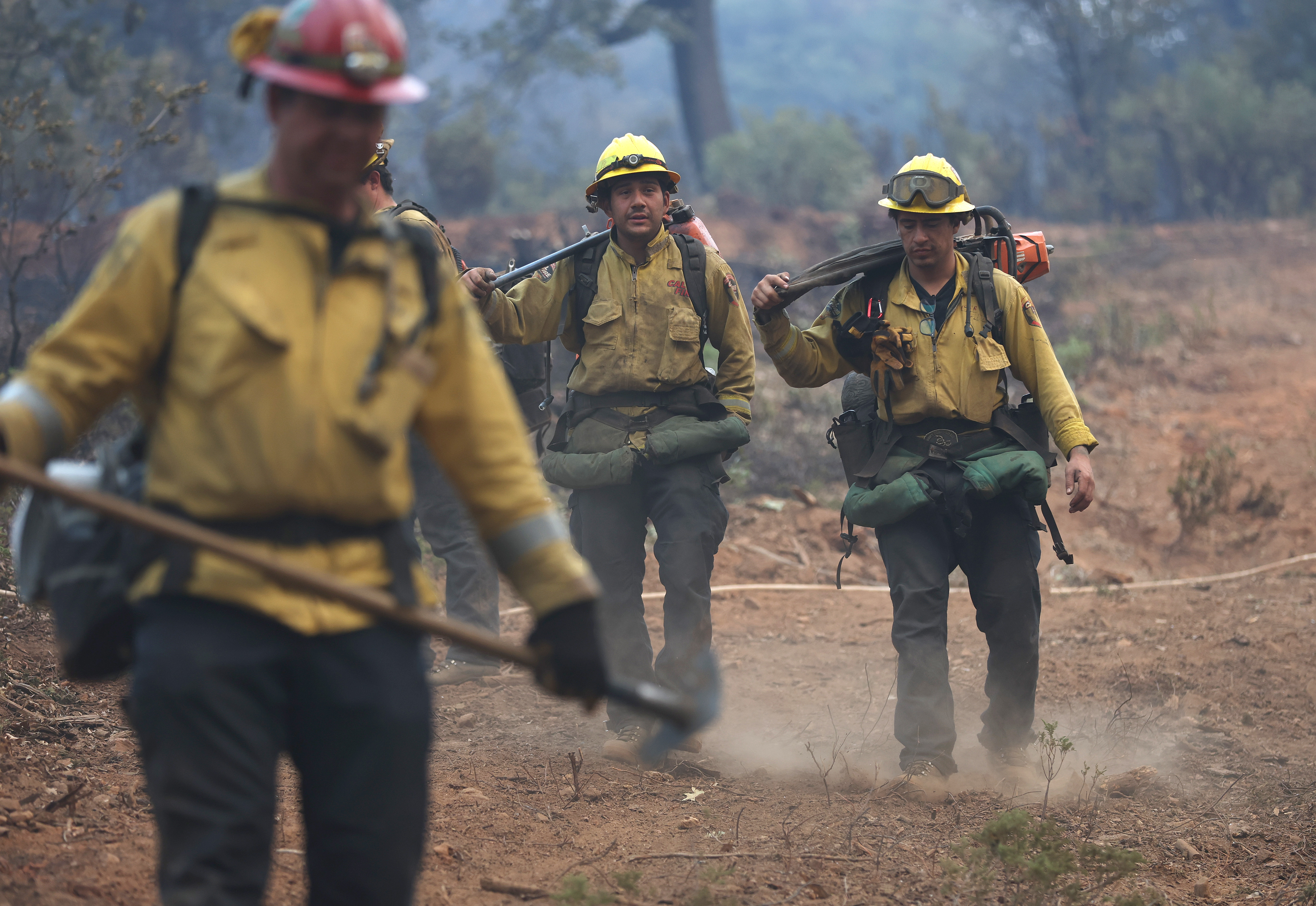 Cal Fire firefighters walk down a hill as they mop up hot spots after the Oak Fire moved through the area on Monday, July 25, 2022 near Jerseydale, Calif. 