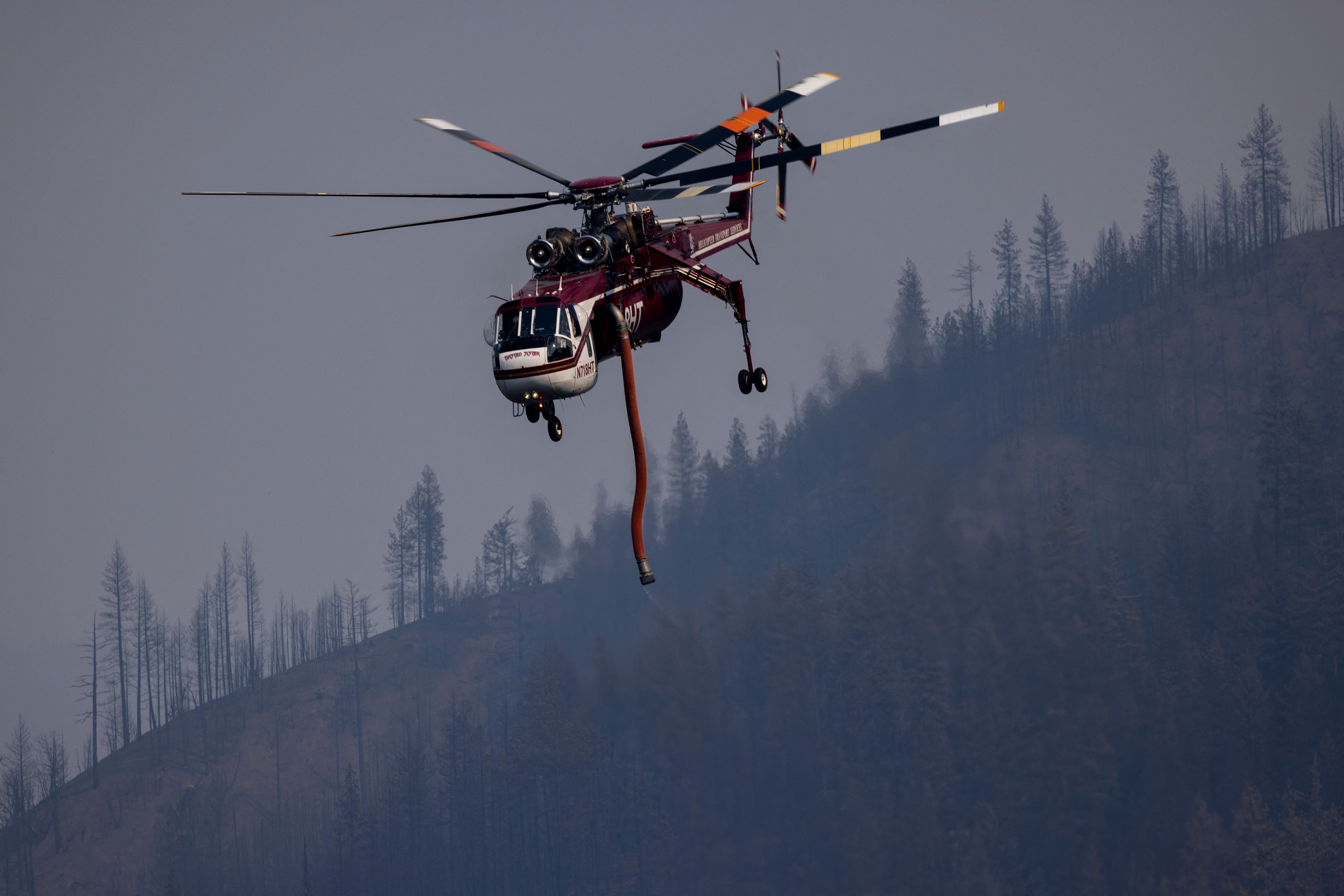 A firefighting helicopter flies to draws water from the Klamath River to fight the McKinney Fire