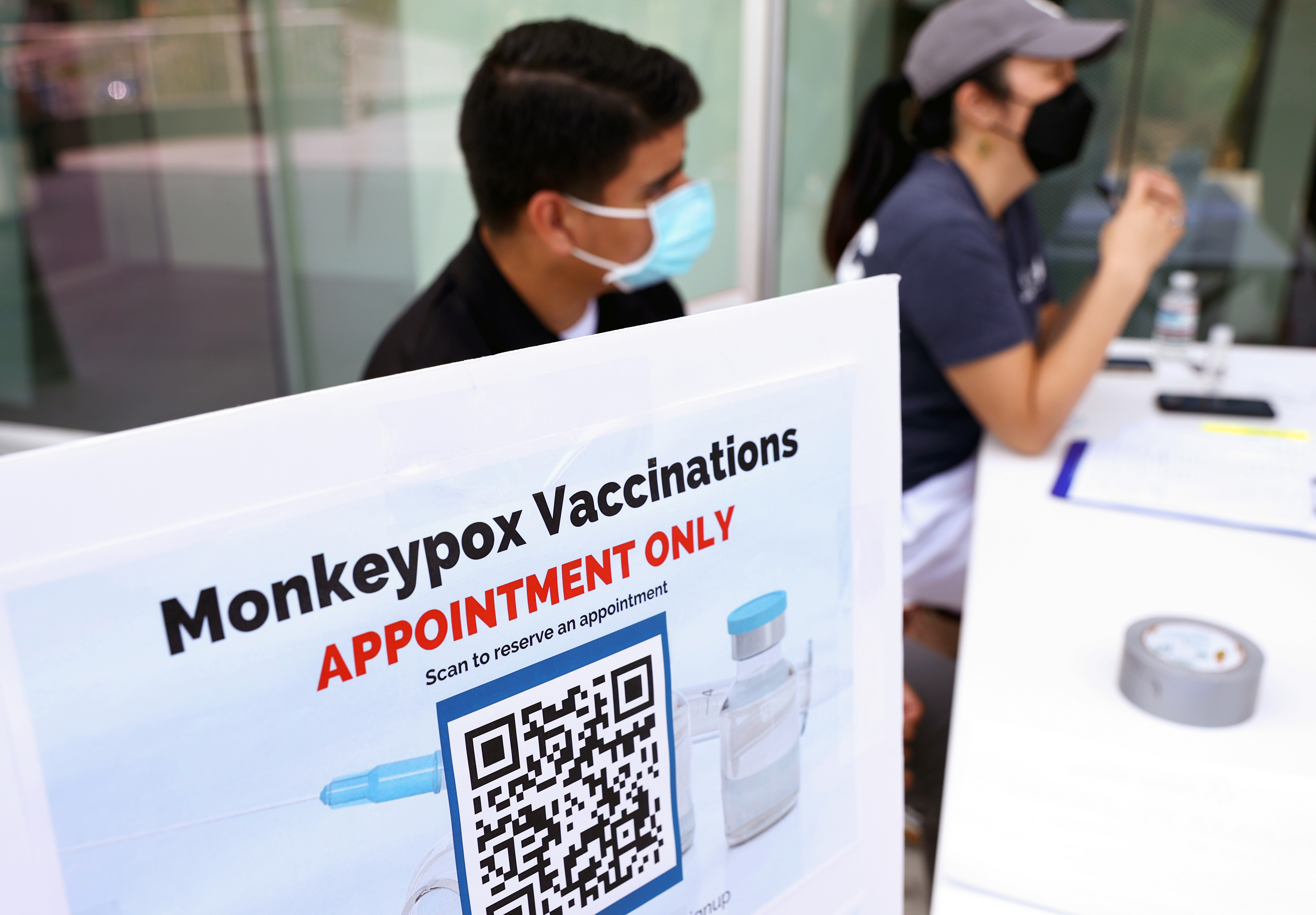 Health workers sit at a check-in table at a pop-up monkeypox vaccination clinic, operated by the Los Angeles County Department of Public Health, at the West Hollywood Library on Aug. 3, 2022, in West Hollywood, Calif. 