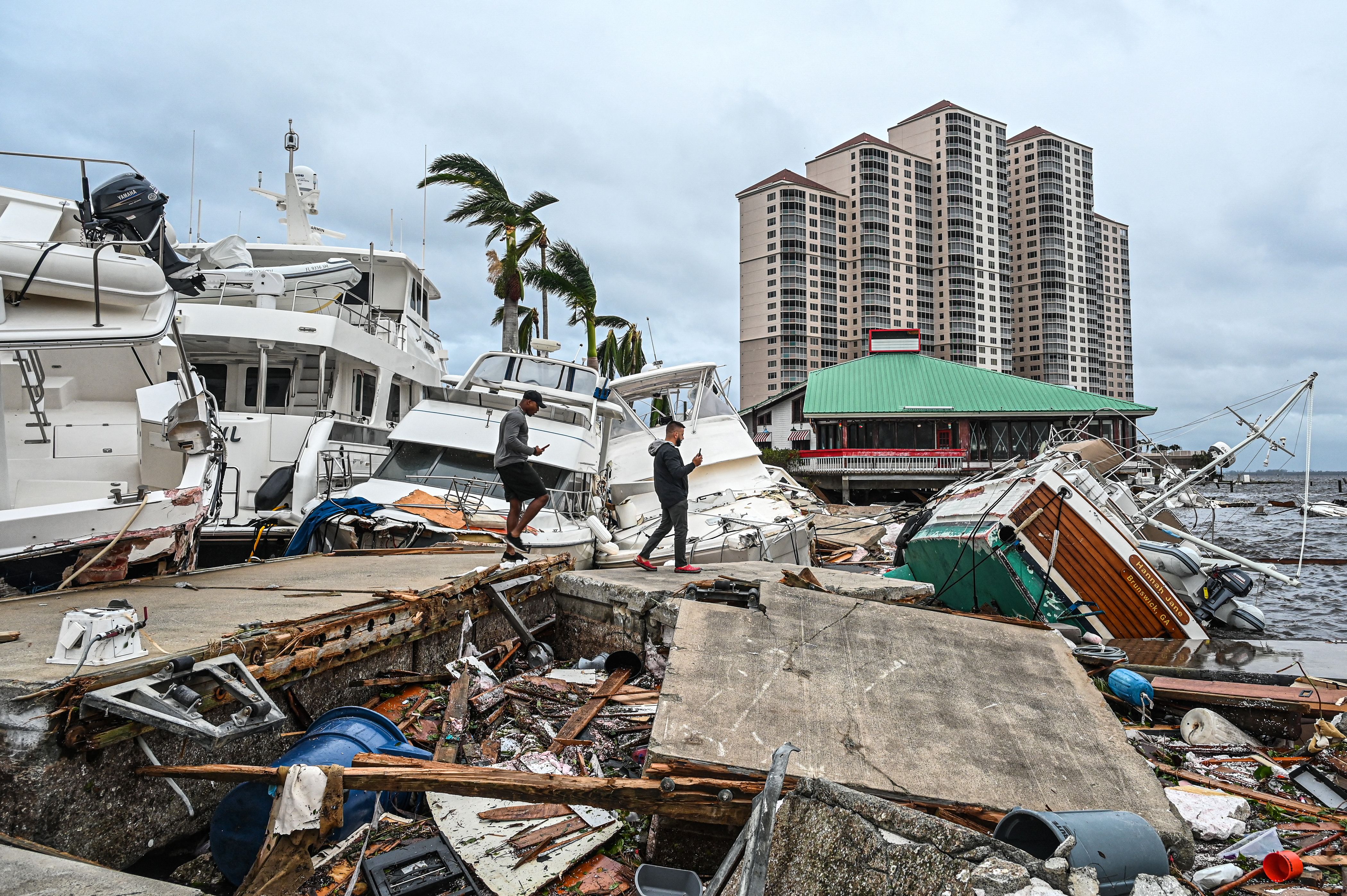 Residents inspect damage to a marina as boats are partially submerged in the aftermath of Hurricane Ian in Fort Myers, Fla., on September 29, 2022.