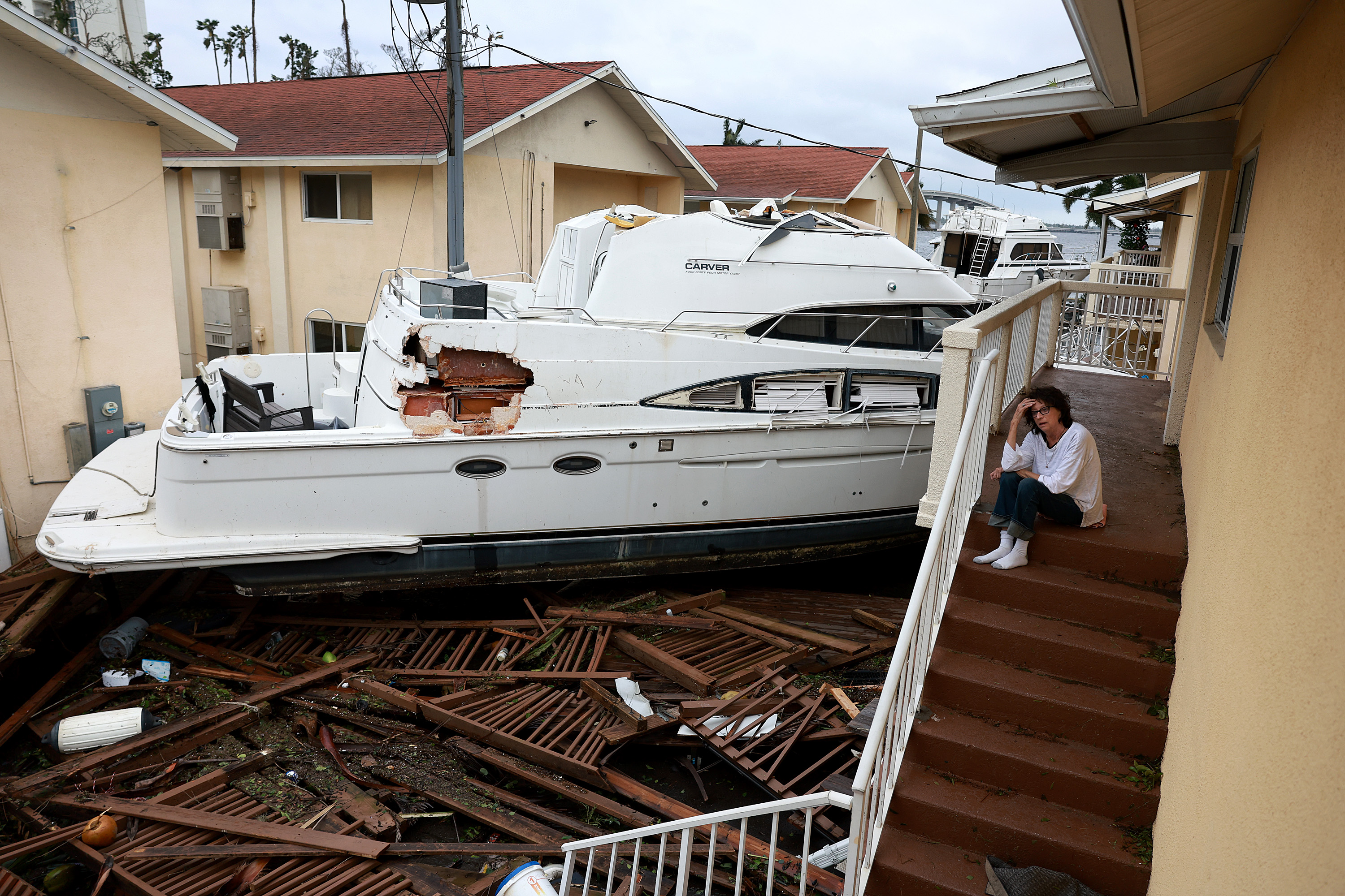 FORT MYERS FLORIDA - SEPTEMBER 29: Brenda Brennan sits next to a boat that pushed against her apartment when Hurricane Ian passed through the area on September 29, 2022 in Fort Myers, Florida. Mrs. Brennan said the boat floated in around 7pm. The hurricane brought high winds, storm surge and rain to the area causing severe damage. (Photo by Joe Raedle/Getty Images)