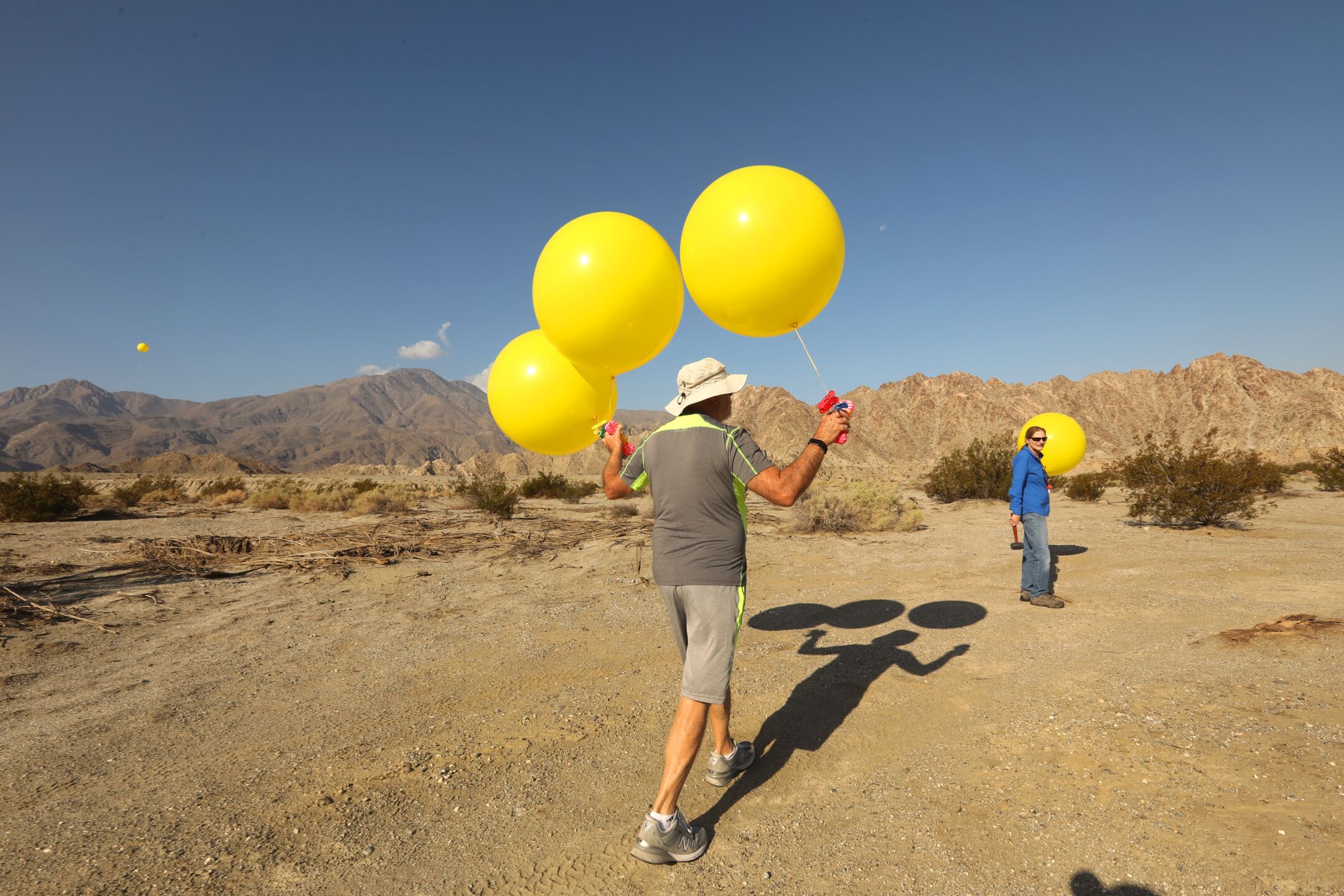 Alena Callimanis, right, and other opponents of the project place balloons at the site of the proposed surf park at the height of the lamps that will light the pool.