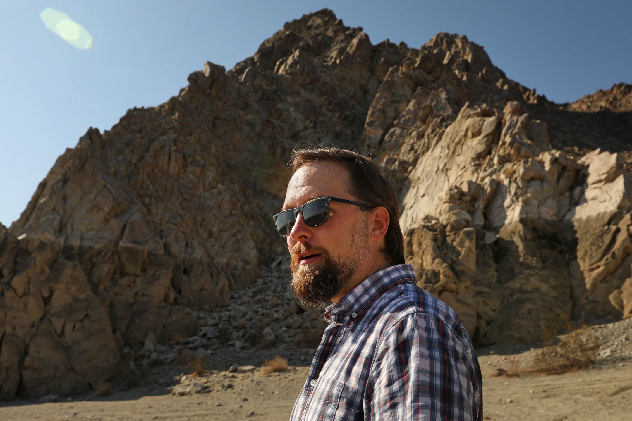 Naturalist Colin Barrows stands in front of the dark line on Coral Mountain that marks the ancient shoreline of Lake Cahuilla.