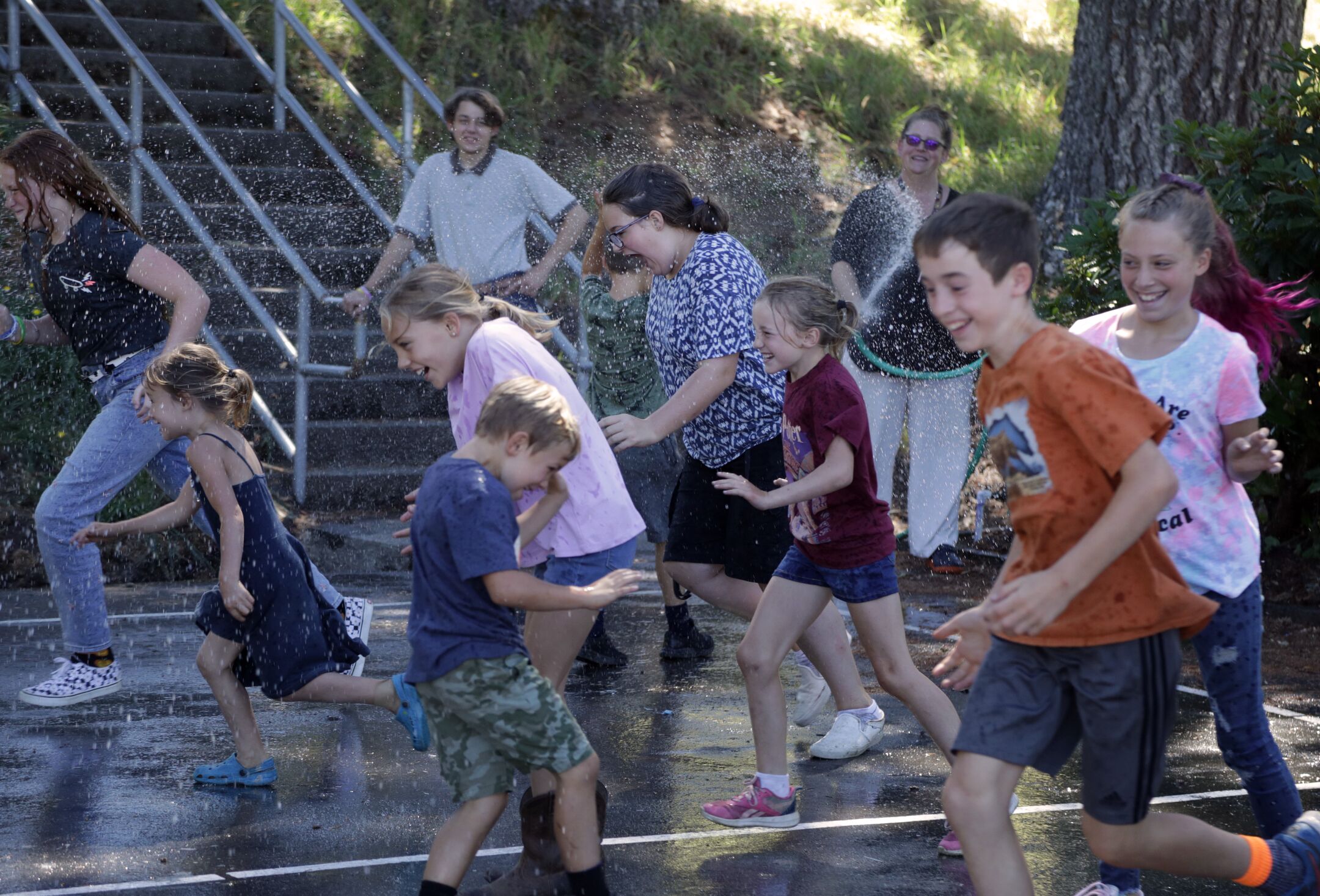 Supt. Greta Turney, rear, sprays students with a garden hose during their physical education period on a hot August afternoon.