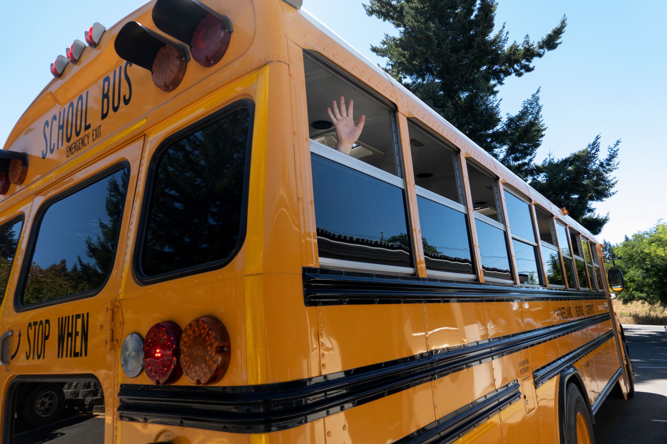 A student waves as the school bus leaves Kneeland Elementary School.