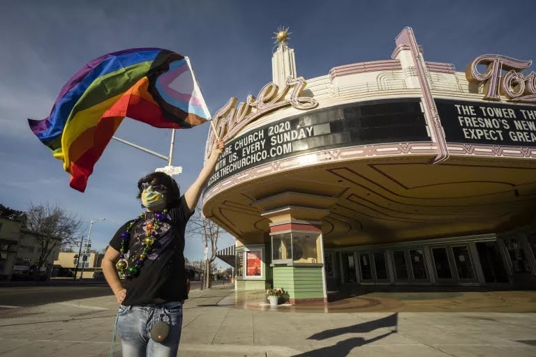 Ronnie Cassis raises a gay pride flag in front of the Tower Theatre in Fresno.