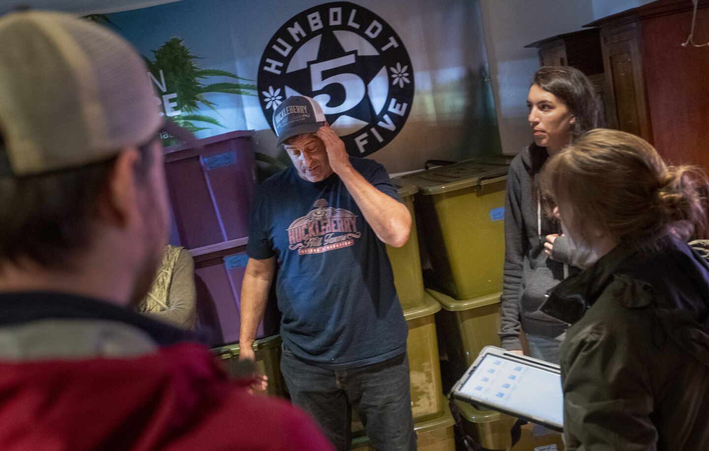Johnny Casali, second from left, and partner Rose Moberly, second from right, talk with inspectors from the California Department of Cannabis Control inside a storage room at Casali's Huckleberry Hill Farms in November.