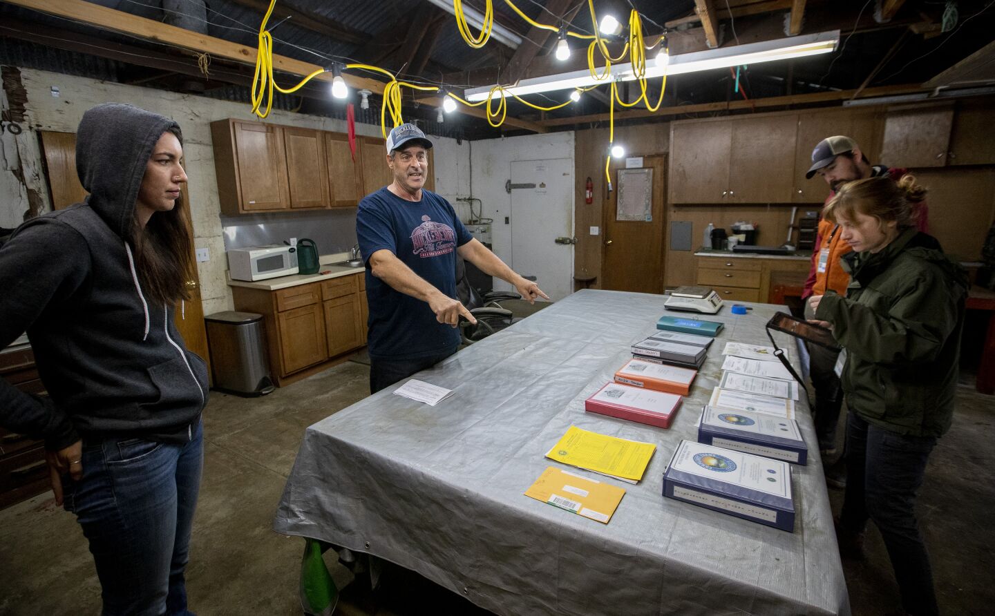 Johnny Casali, second from left, with partner Rose Moberly, left, points out Metrc data logs for state inspectors Eric LeBlanc, second from right, and Laura Powell during a recent inspection of his Humboldt County farm.