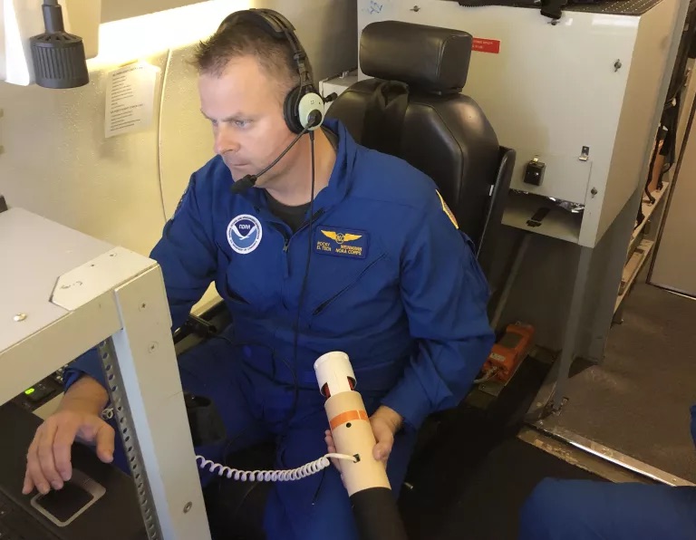 Rocky Weinmann, a drop operator for the National Oceanic and Atmospheric Administration, prepares to deploy a dropsonde from the plane over an atmospheric river.