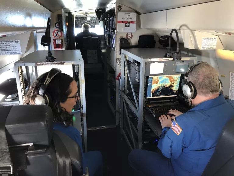 Meteorologists Sofia de Solo and Rich Henning look at a map showing their path toward an atmospheric river as they set out on a NOAA reconnaissance flight.