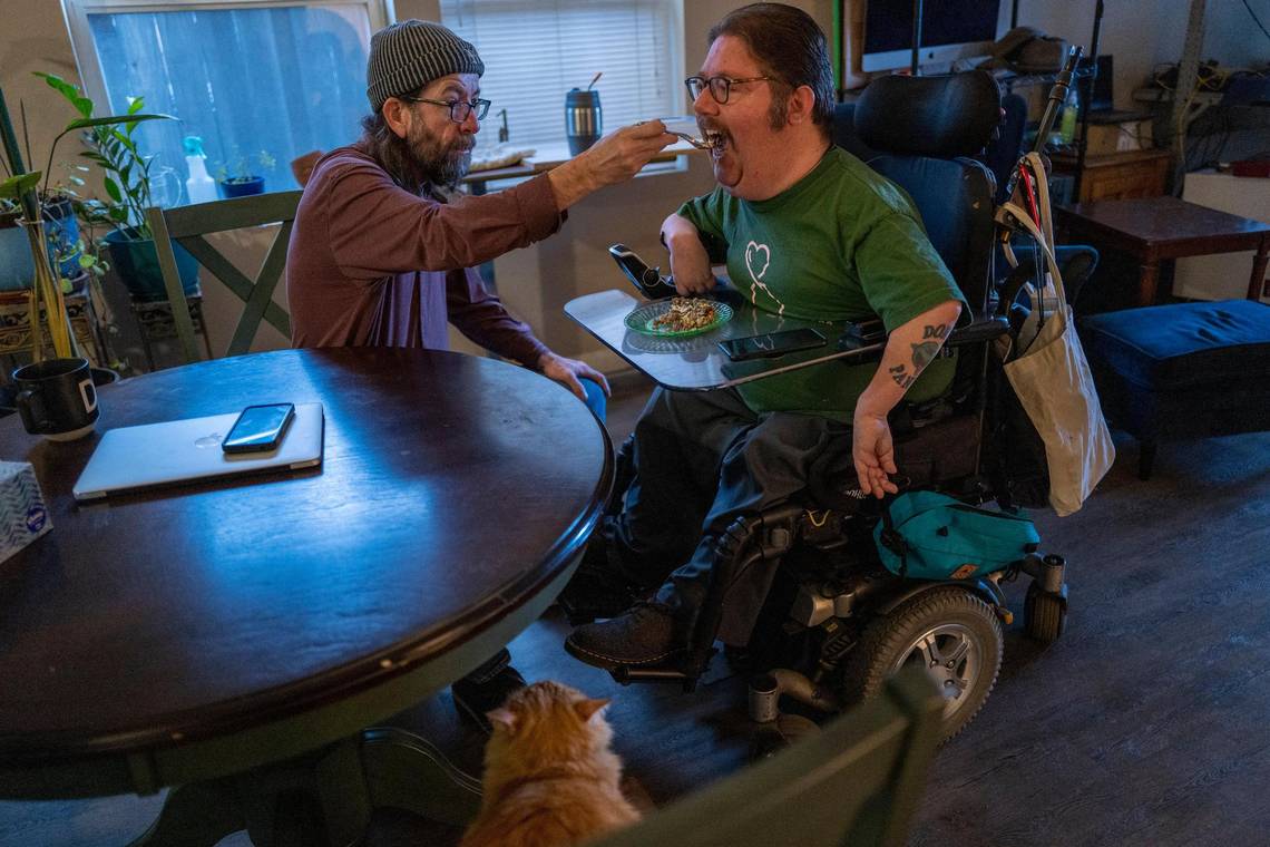 Russell Rawlings, 46, right, a disability rights advocate who lives with cerebral palsy and relies on caregivers from California's In-Home Supportive Services, is fed breakfast by his caregiver Darrow Sprague, 54, on Tuesday.