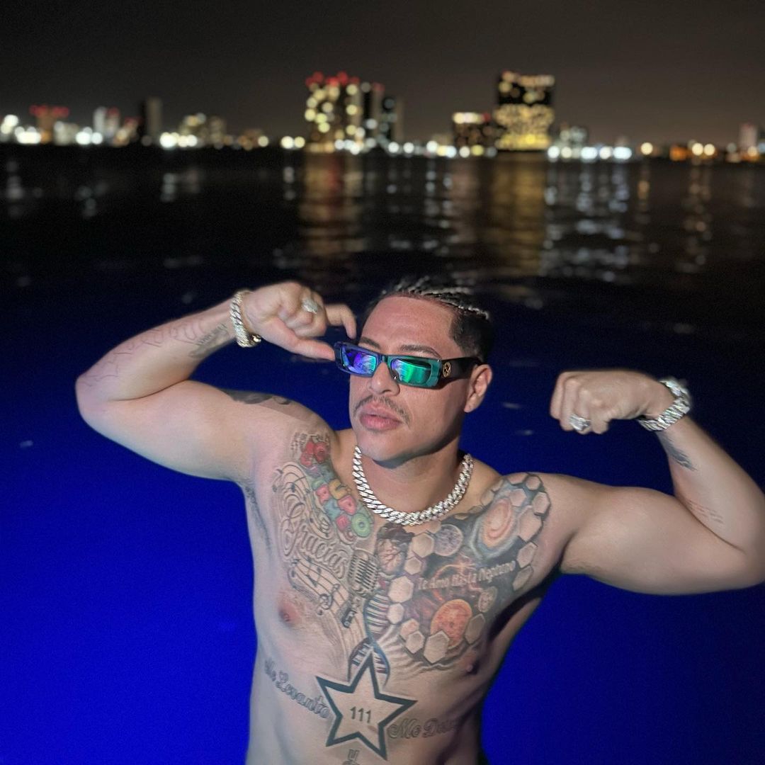 Eduin Caz showing muscle and tattoo in a swimming pool