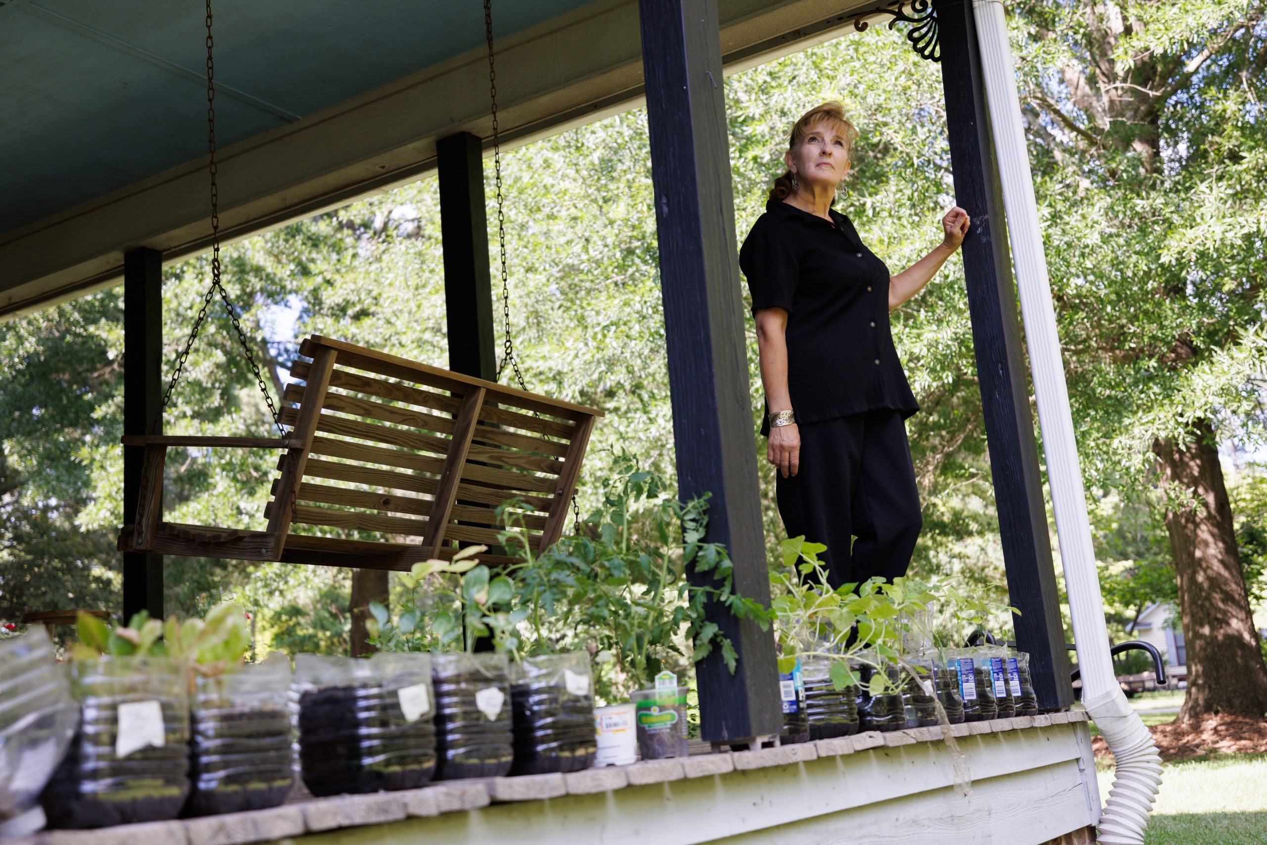 Jamie White on the porch of her Gray's Creek home with plants in water bottles