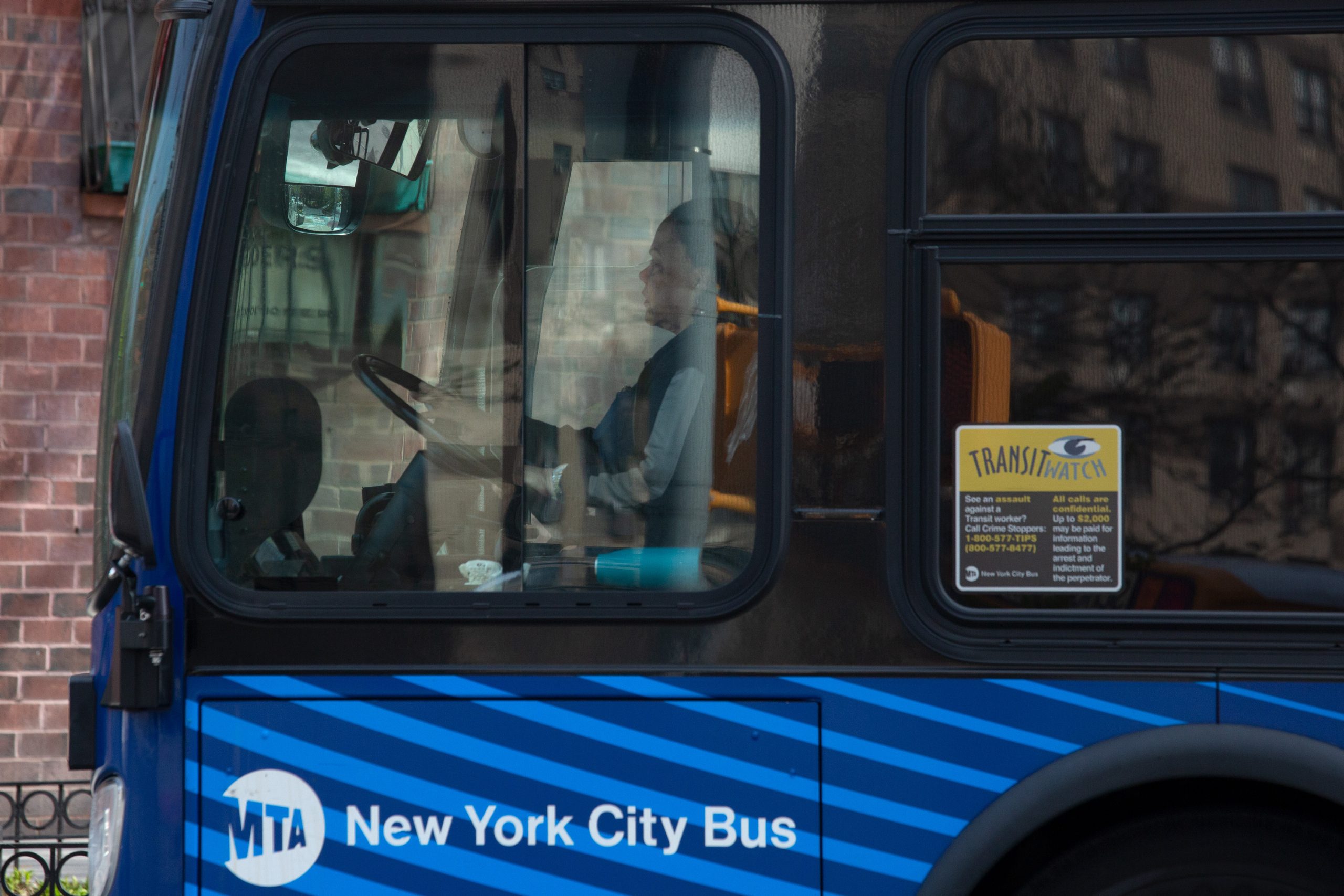 A female bus operator drives down Fulton Street in Brooklyn.