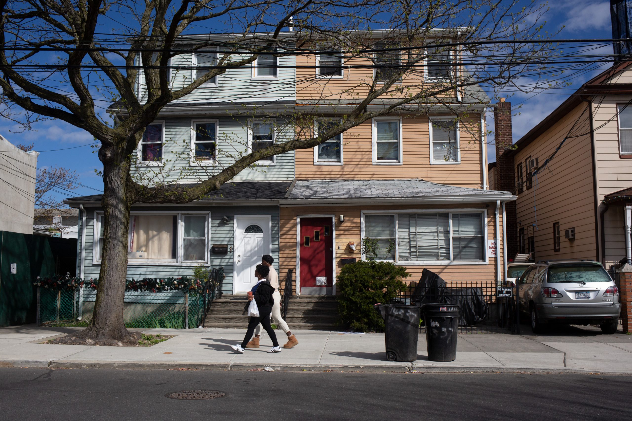 Two people walk together down a residential block in Jamaica.