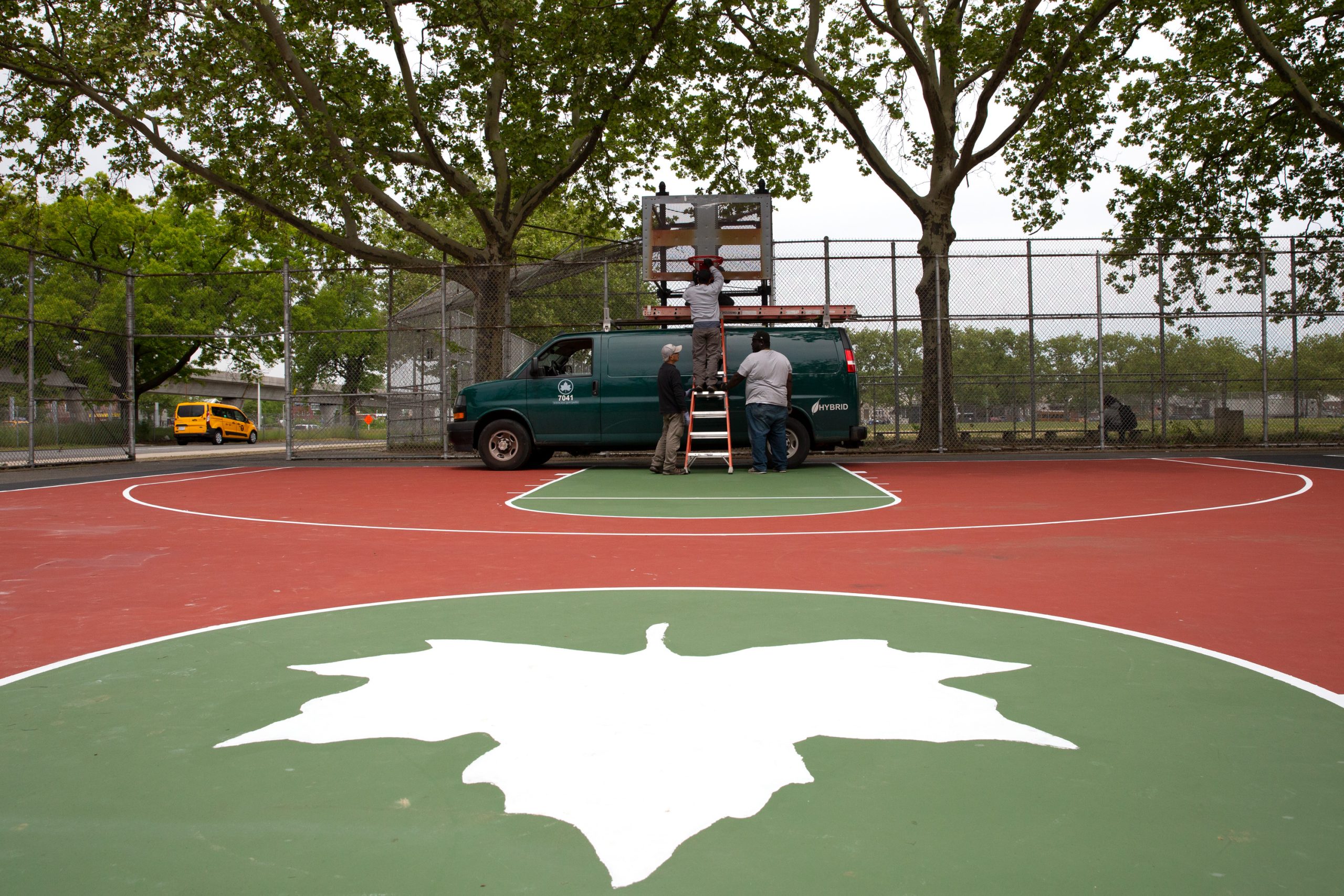Parks Department workers install new hoops at Dr. Charles R. Drew Park in Jamaica.