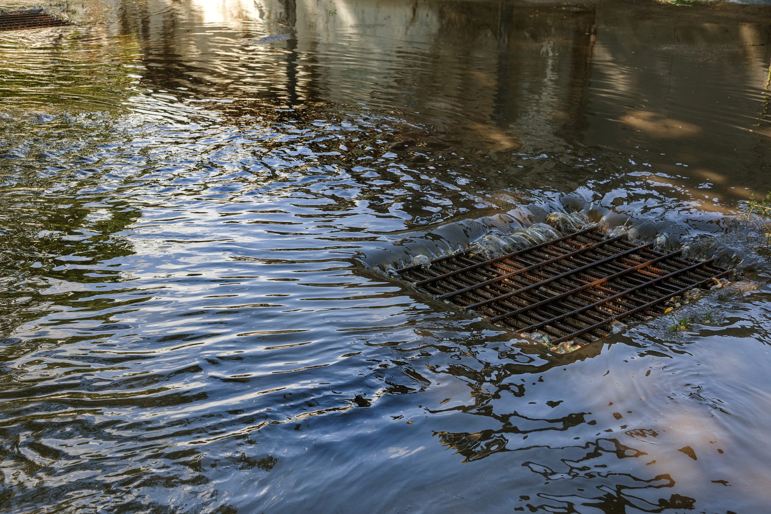 Water flows into a sewer grate during a heavy rain.