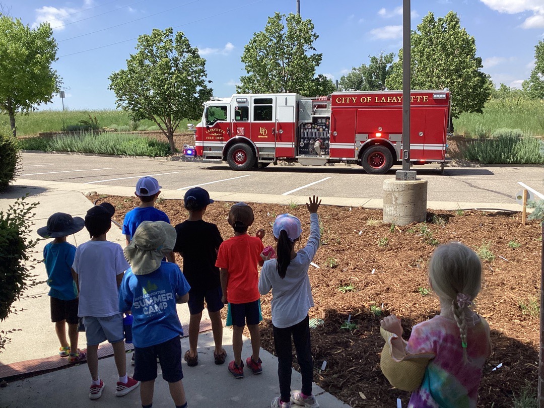 A group of children wave goodbye to a visiting Fire Truck