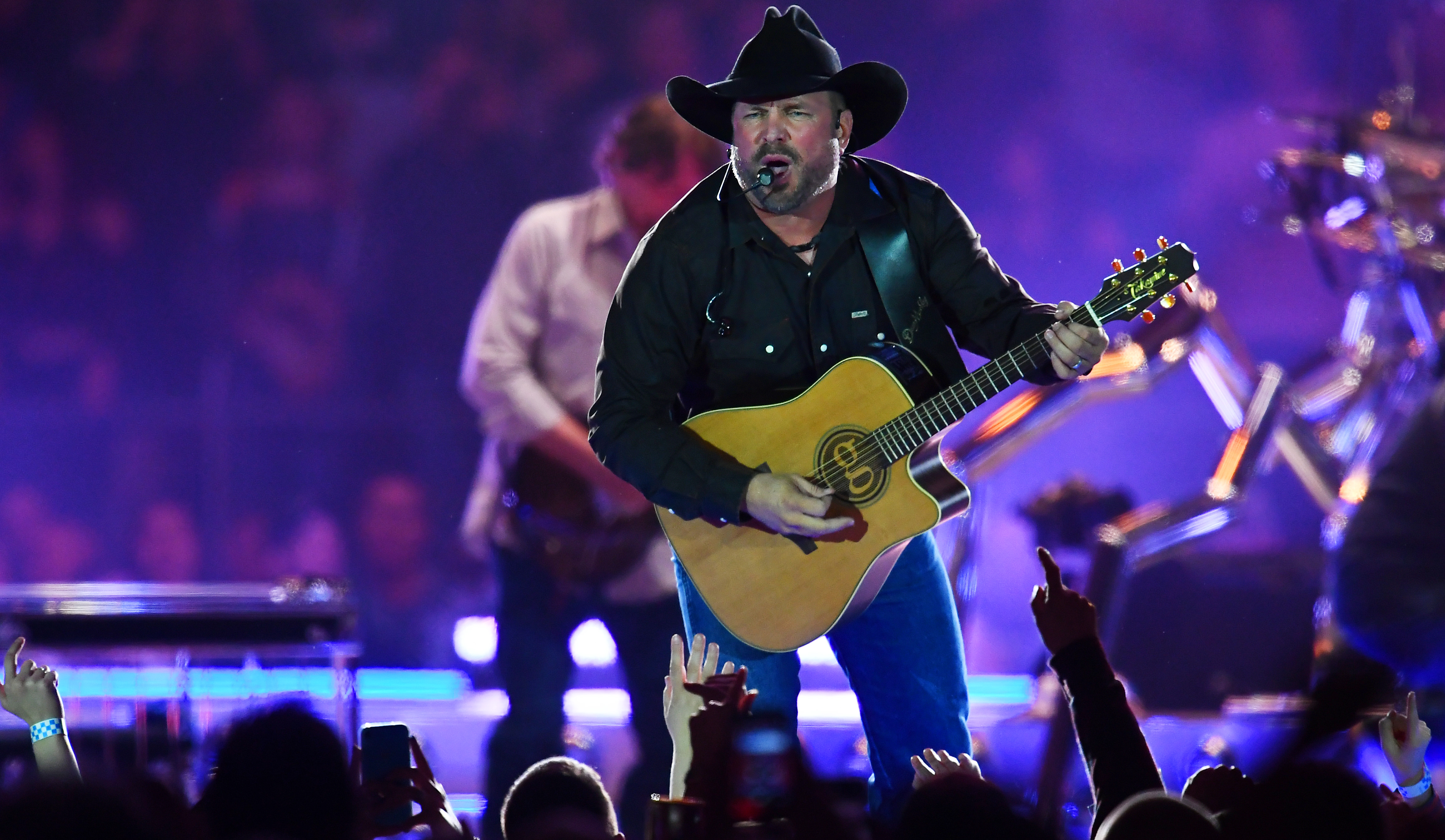 Garth Brooks plays guitar and sings. 