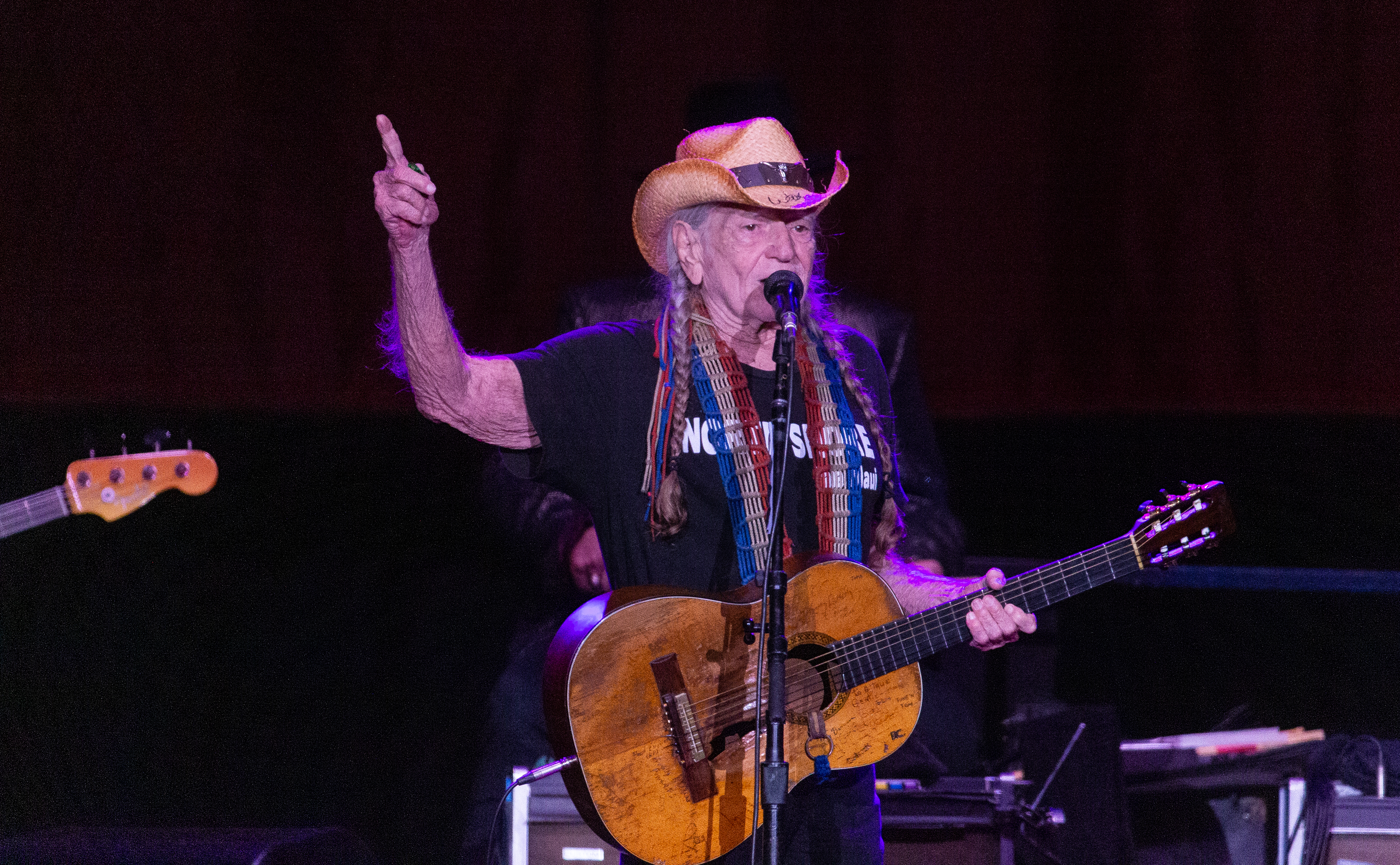 Willie Nelson points up while singing.
