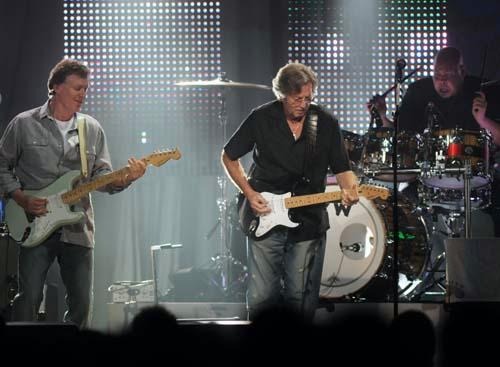Steve Winwood and Eric Clapton play guitar.