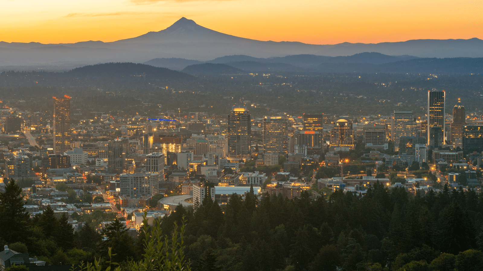 An image of a city with a mountain and sunset in the background.