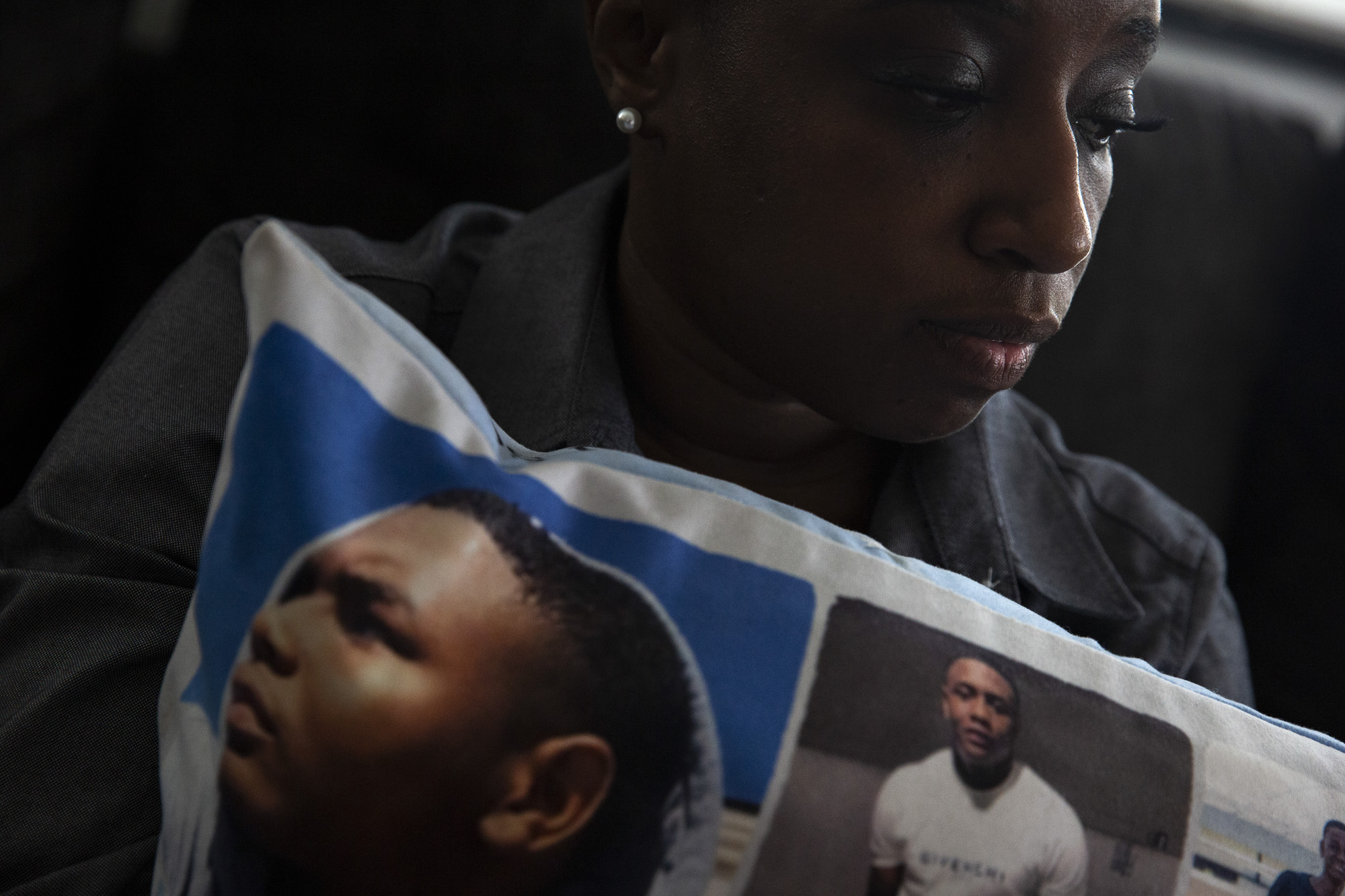 Jennifer Maraston holds a pillow covered in photos of her son Jaquan Wyatt, who was murdered the day after he turned 21 while traveling in California. It has been nearly two years since his homicide, but court proceedings have been delayed by challenges involving COVID-19 and the amount of people charged in the case. Photo by Shelby Tauber for CalMatters