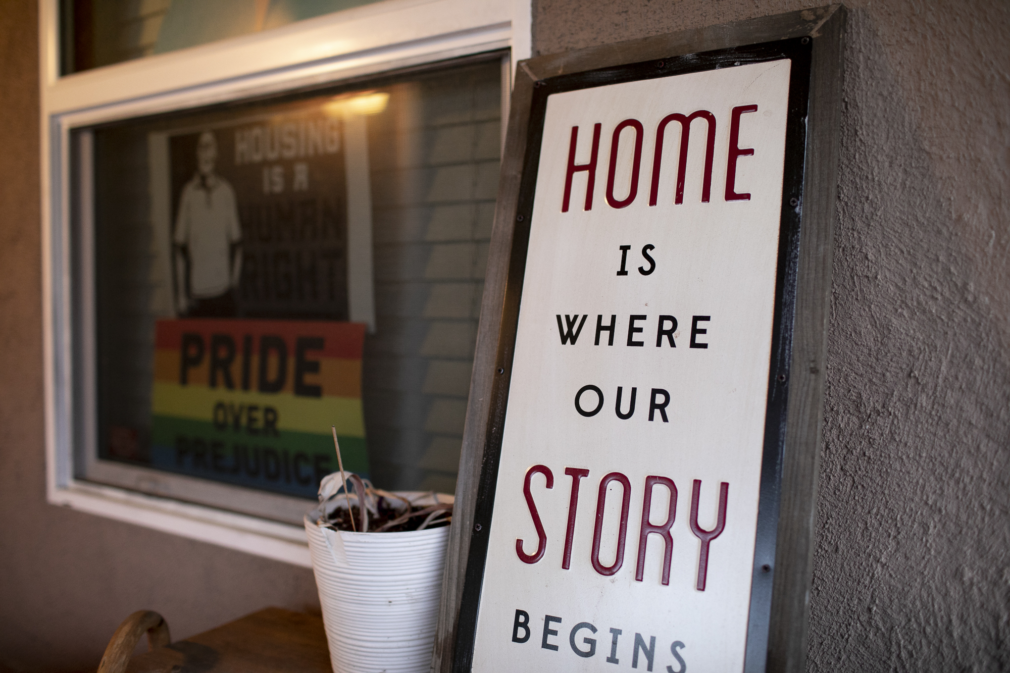 Signs on the front porch of Merika Reagan's Oakland home depicting support for housing rights and gay pride. Photo by Anne Wernikoff, CalMatters