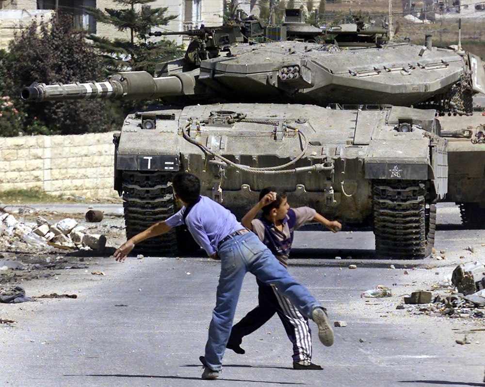 Niños lanzando piedras contra un tanque israelí