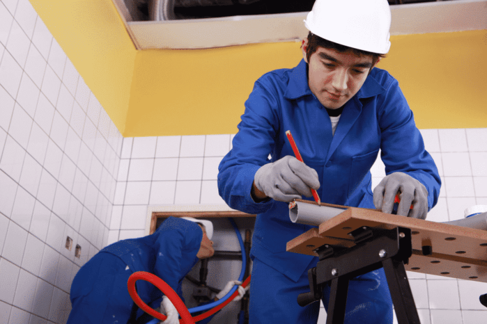 Young plumber cutting grey pipe Plumbing emergency Services