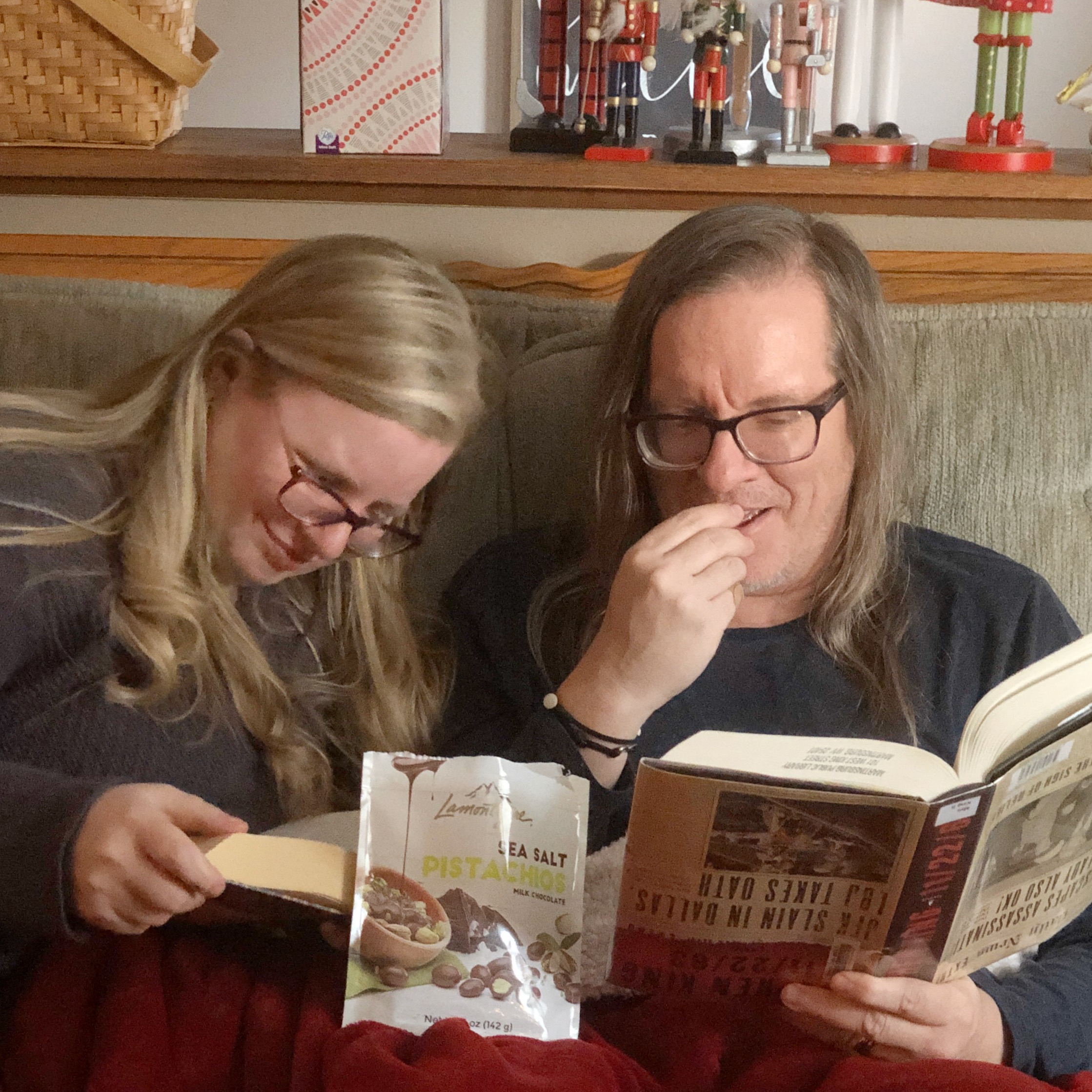 Annie and Will eating chocolates and reading books together on the couch.