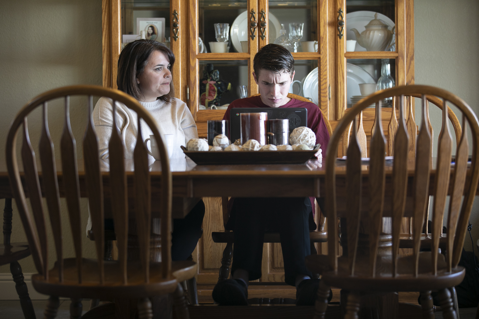 Linda Soares, left, helps her son, Daniel, 16, with his history homework at their dining room table. Soares says that she has been able to learn from her son's school aid, who is a friend, on how to best assist him with his class work. Photo by Anne Wernikoff for CalMatters
