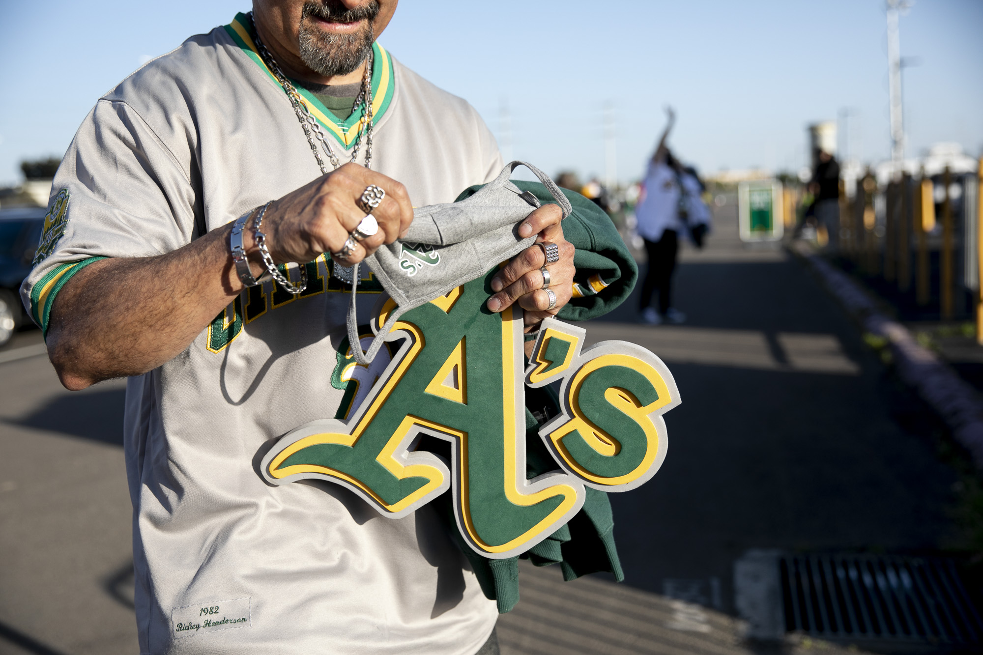 Andrew Rodriguez of Union City organizes his A's swag as her gets in line to enter the stadium before the start of the game. Photo by Anne Wernikoff, CalMatters