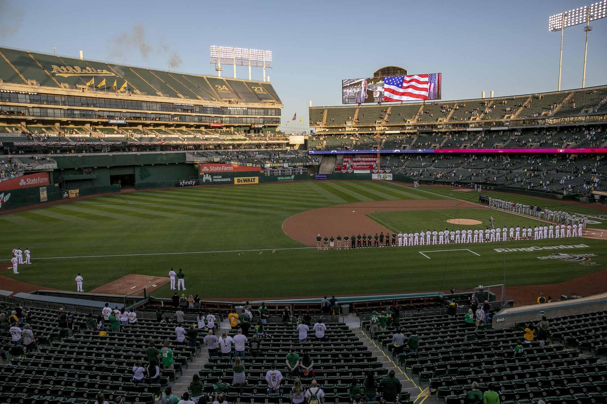 Players and spectators stand for the national anthem at the start of the game between the Oakland A's and the Houston Astros. Oakland Coliseum operated at 26% capacity in order to allow ample spacing between groups. Photo by Anne Wernikoff, CalMatters