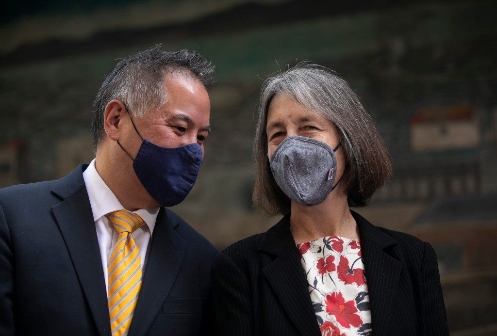 Assembly Budget Committee chairperson Phil Ting, left, whispers to Senate Budget Committee chairperson Nancy Skinner during a press conference at The Unity Council in Oakland where Gov. Gavin Newsom announced additional stimulus checks with the state surplus on May 10, 2021. Photo by Anne Wernikoff, CalMatters
