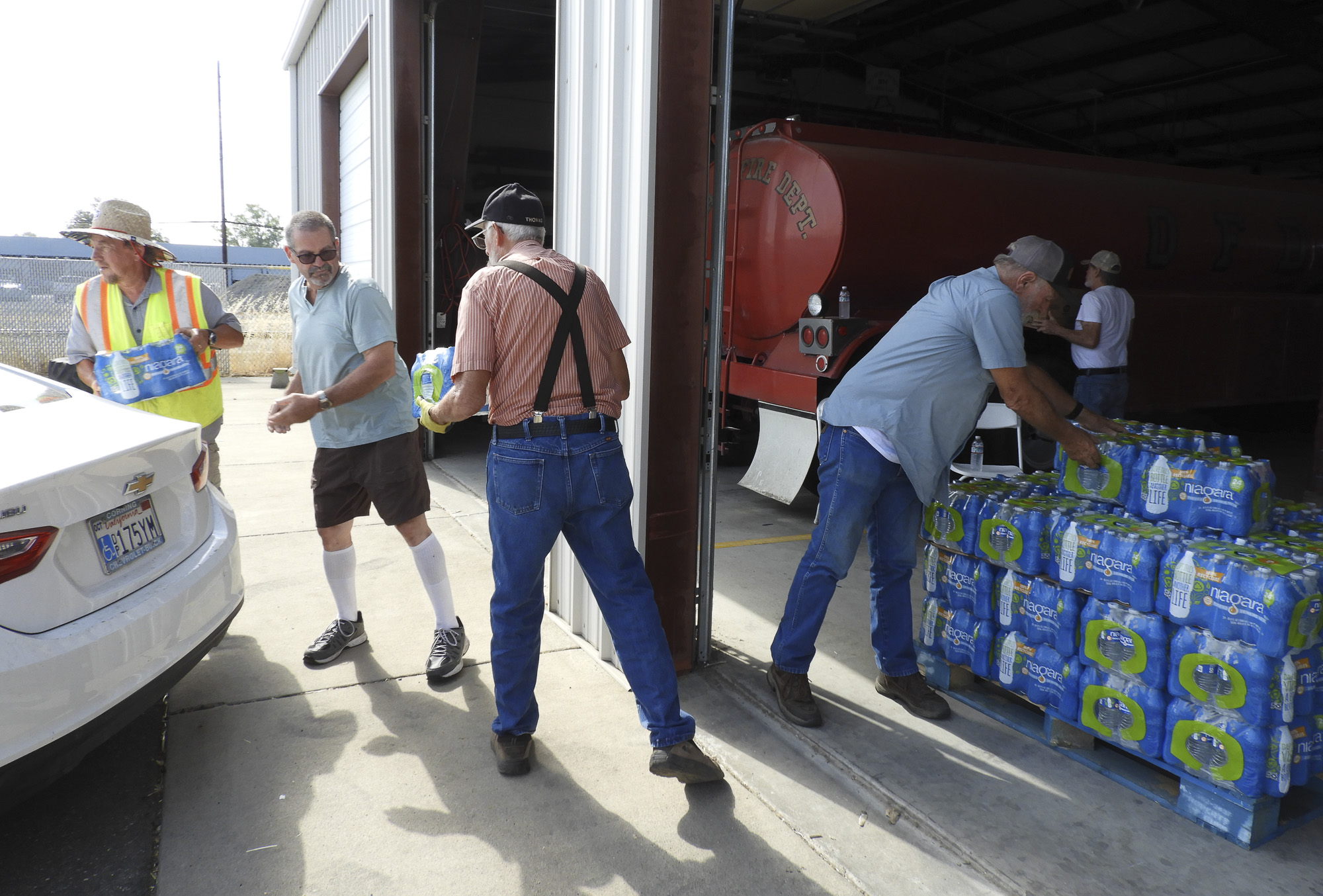 Volunteers distribute bottled water supplies to people with dry wells at the Orland Fire Department in Glenn County on July 28, 2021. Some volunteers were dealing with well outages, themselves. Photo by Rachel Becker, CalMatters