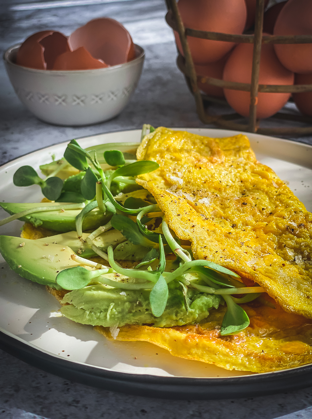 avocado and greens omelette, basket of eggs and bowl of egg shells