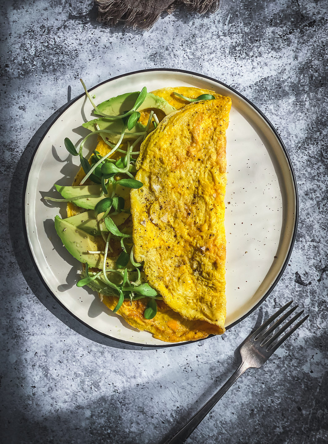 avocado and greens omelette on table with fork