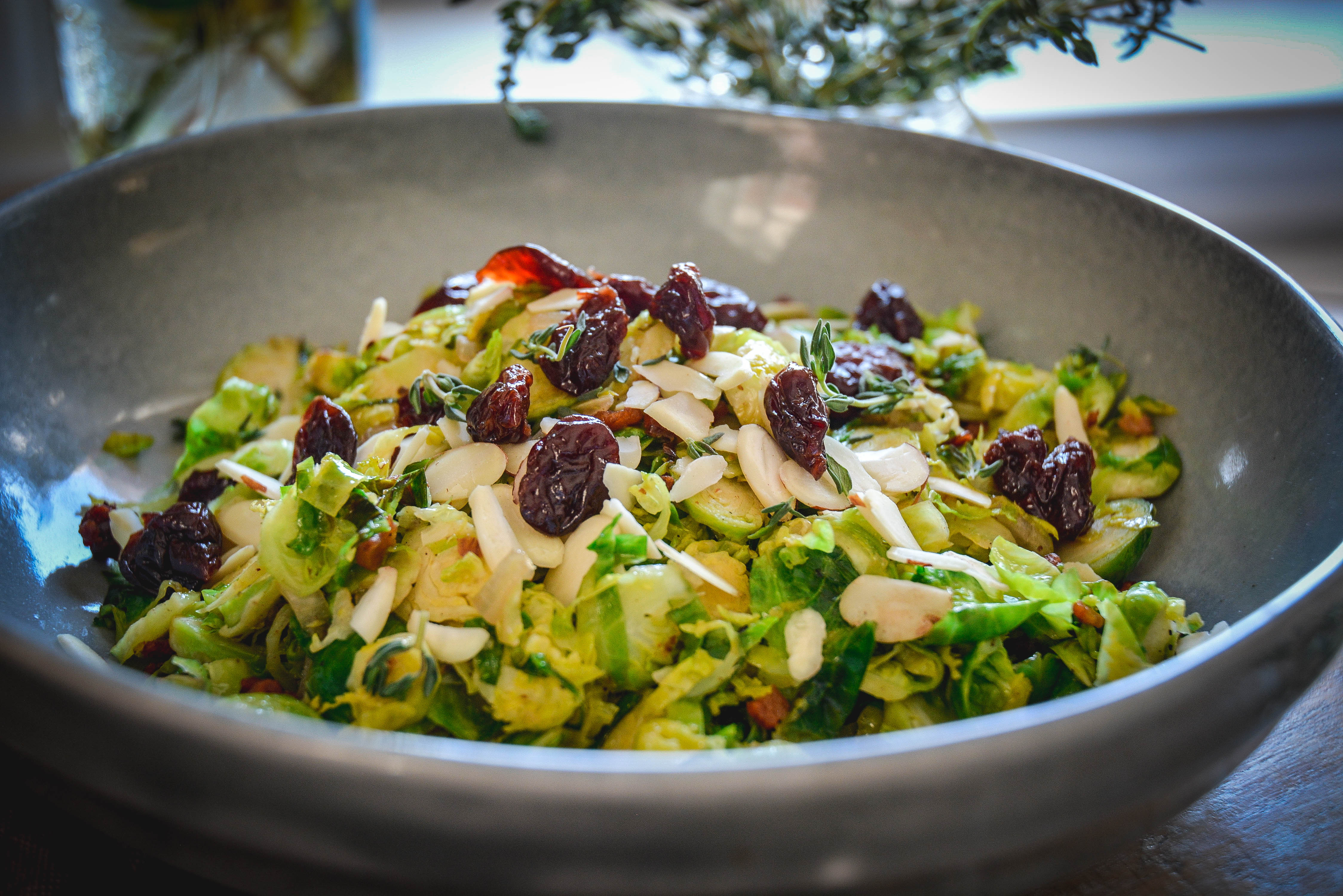 Warm Brussels Sprouts Salad with Bacon and Dried Cherries in grey bowl