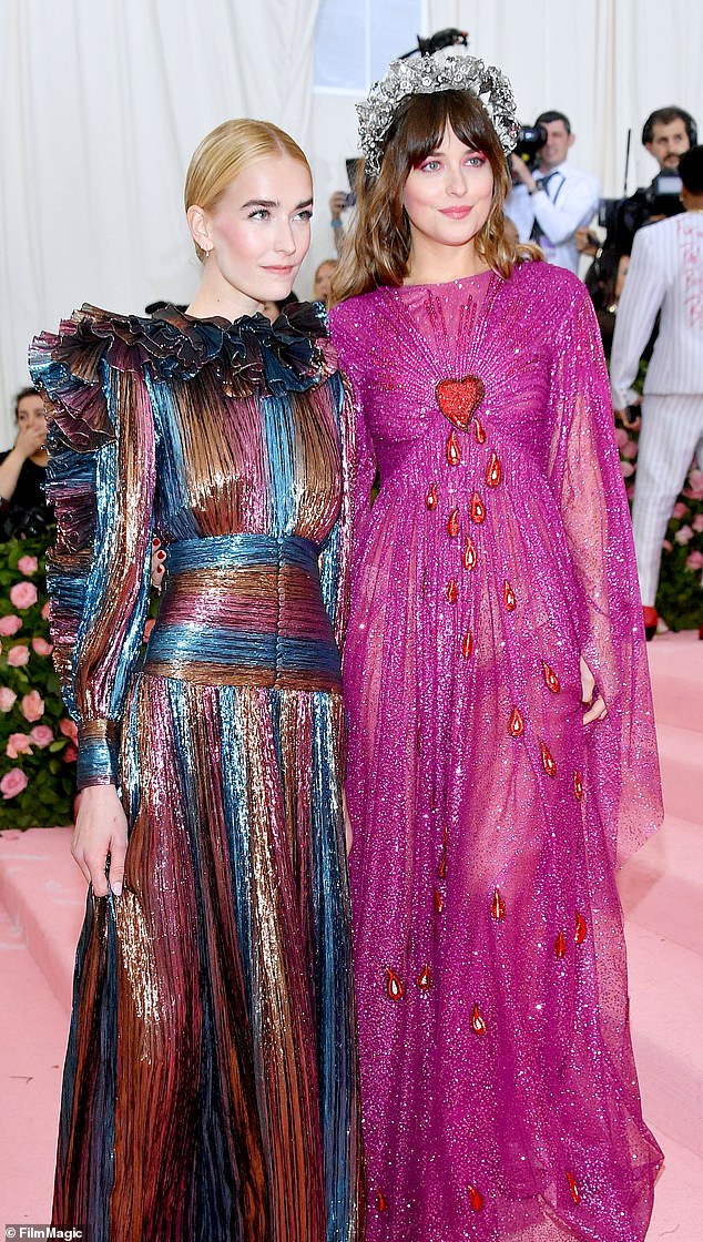 Dakota Johnson, 29, holds hands with younger sister Grace, 19, as they