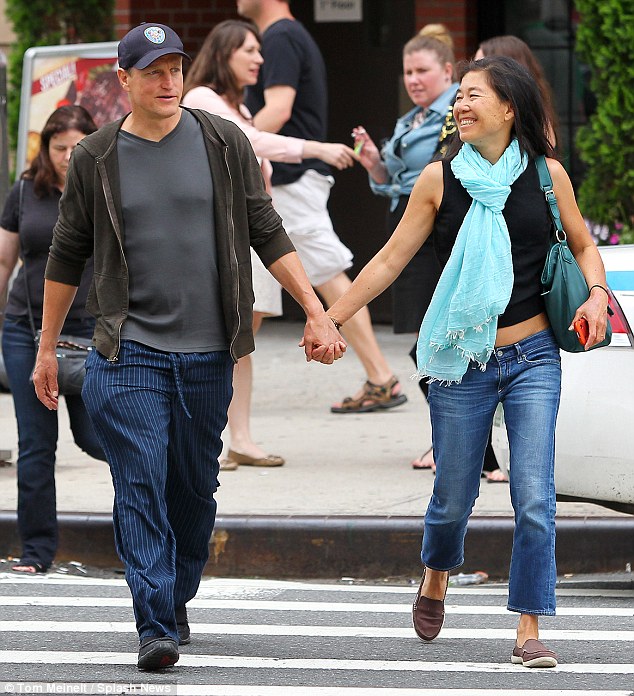 Woody Harrelson grins as he walks hand in hand with his wife Laura